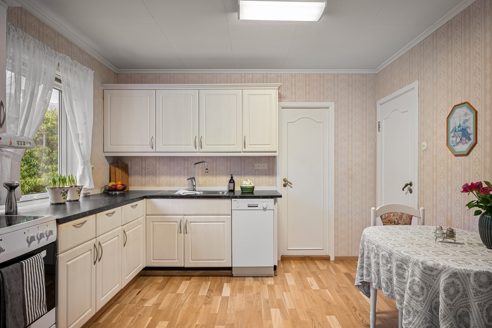 Et romslig kjøkken fornyet i ca. 2016 som innbyr til sosial samling med både lite spisebord og en lounge for avslapning. Rikelig med skapplass og arbeidsbenk. Fint utsyn til egen bakhage og mye naturlig lys. Galleribilde