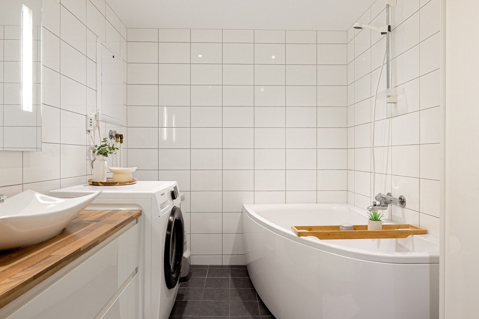 Badet har badekar med dusj, vegghengt toalett, baderomsinnredning, varmtvannstank og opplegg for vaskemaskin. Galleribilde