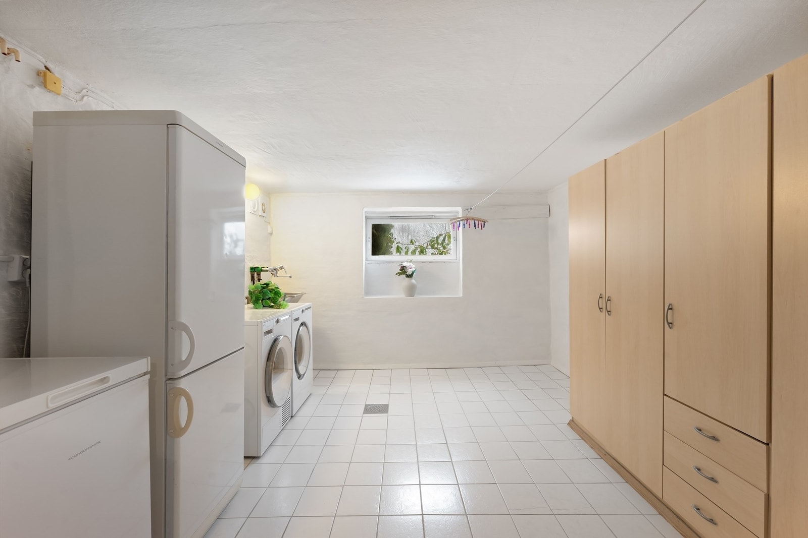 Stort, separat vaskerom med flislagt gulv, utslagsvask og opplegg for vaskemaskin. Galleribilde