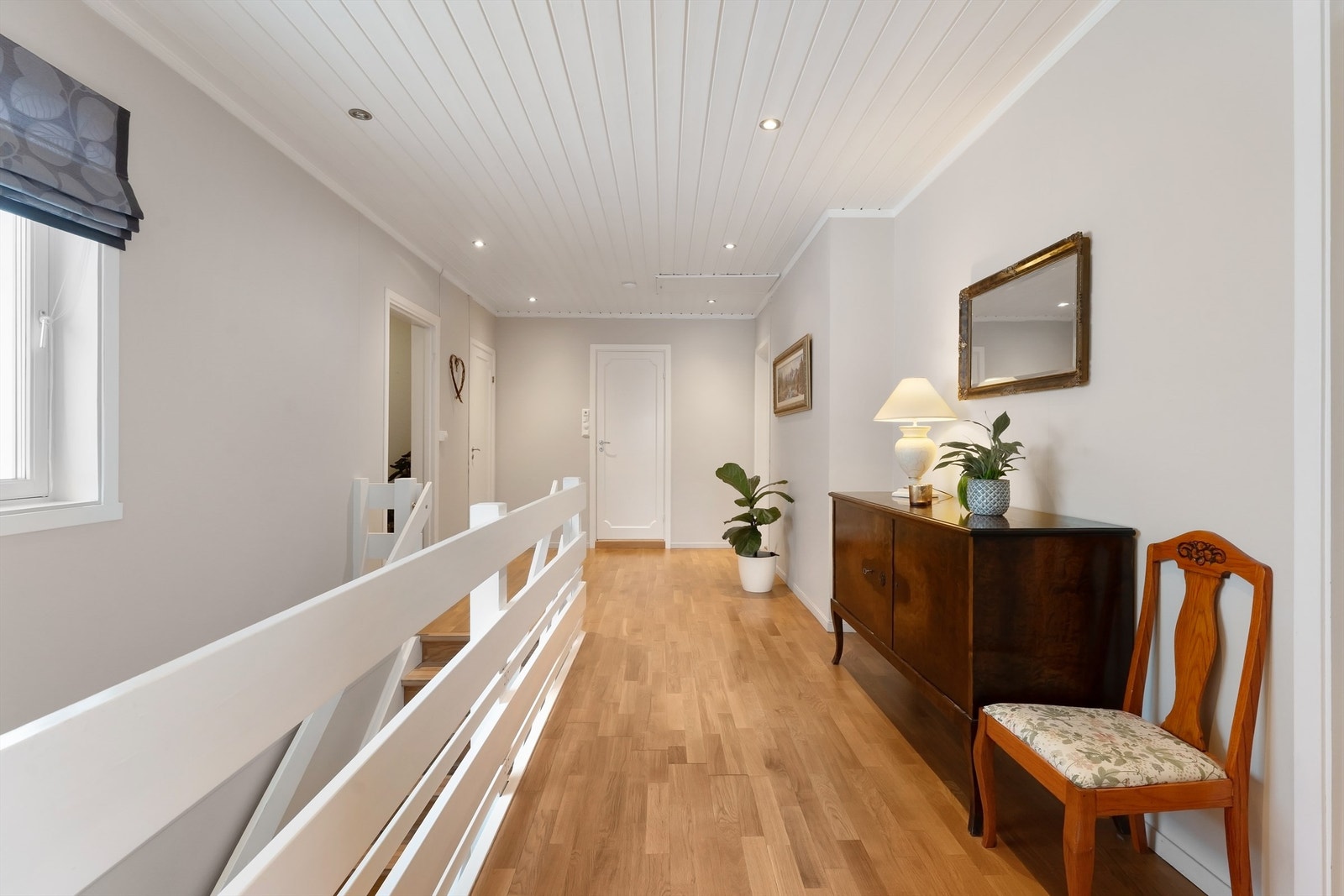 Fra den sentrale gangen med parkettgulv og downlights i himling, åpner boligen seg opp. Galleribilde