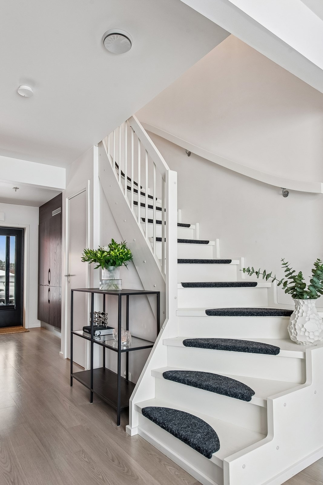 En malt tretrapp leder opp til andre etasje. Under trappen er det en praktisk bod. Galleribilde