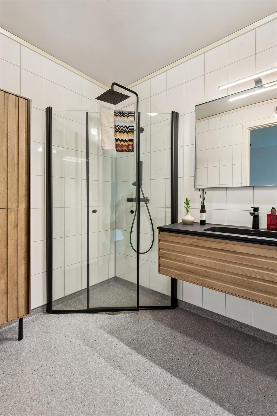 Badet har et moderne uttrykk med baderomsplater på veggene og lekkert dusjhjørne. Galleribilde