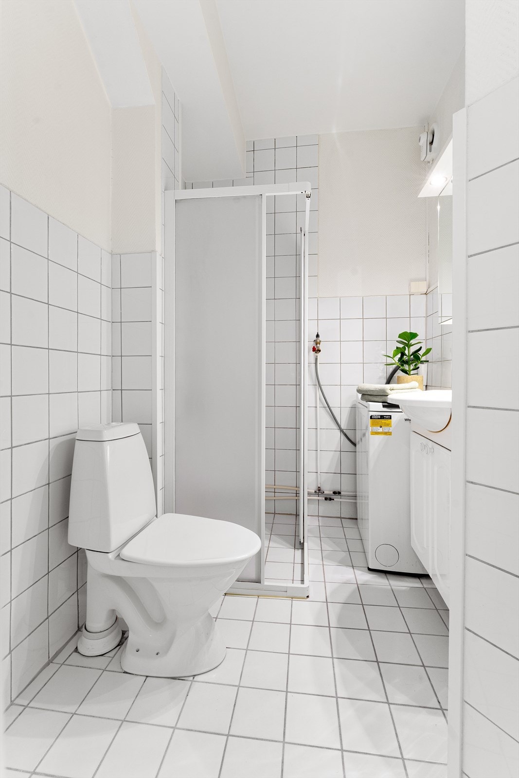 Baderom med tidløse fliser og opplegg for vaskemaskin Galleribilde