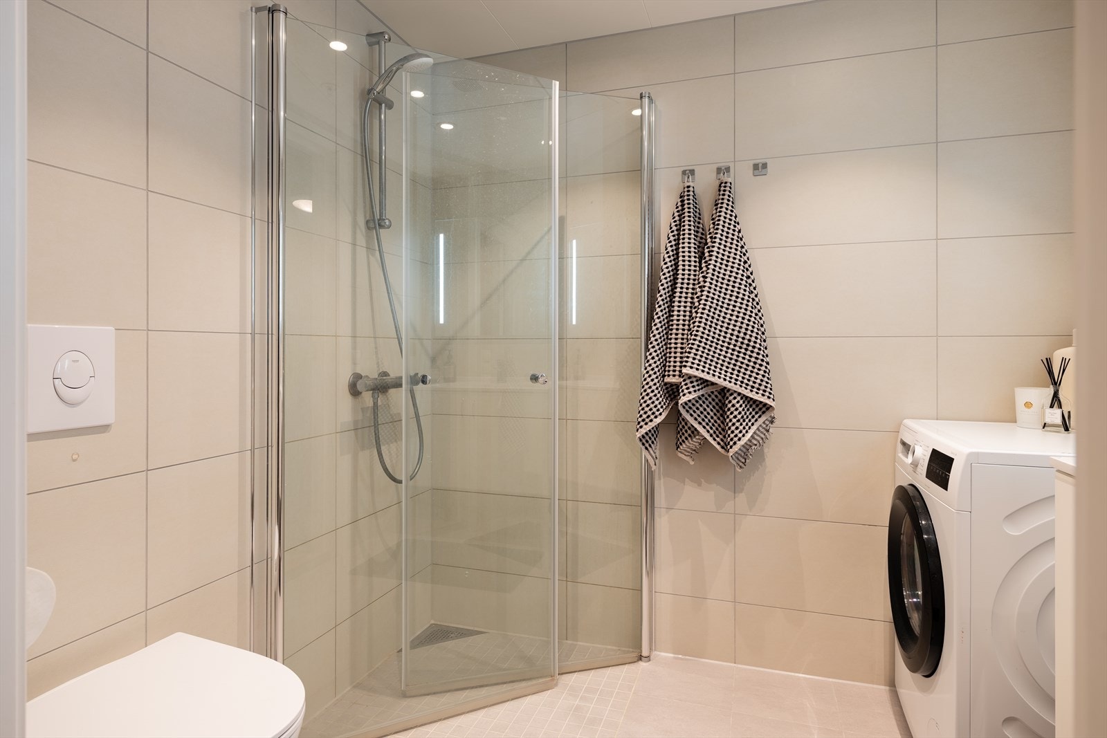 Badet er utstyrt med dusjhjørne, servant, servantskap, opplegg for vaskemaskin, vegghengt wc og rørfordelingsskap. Galleribilde