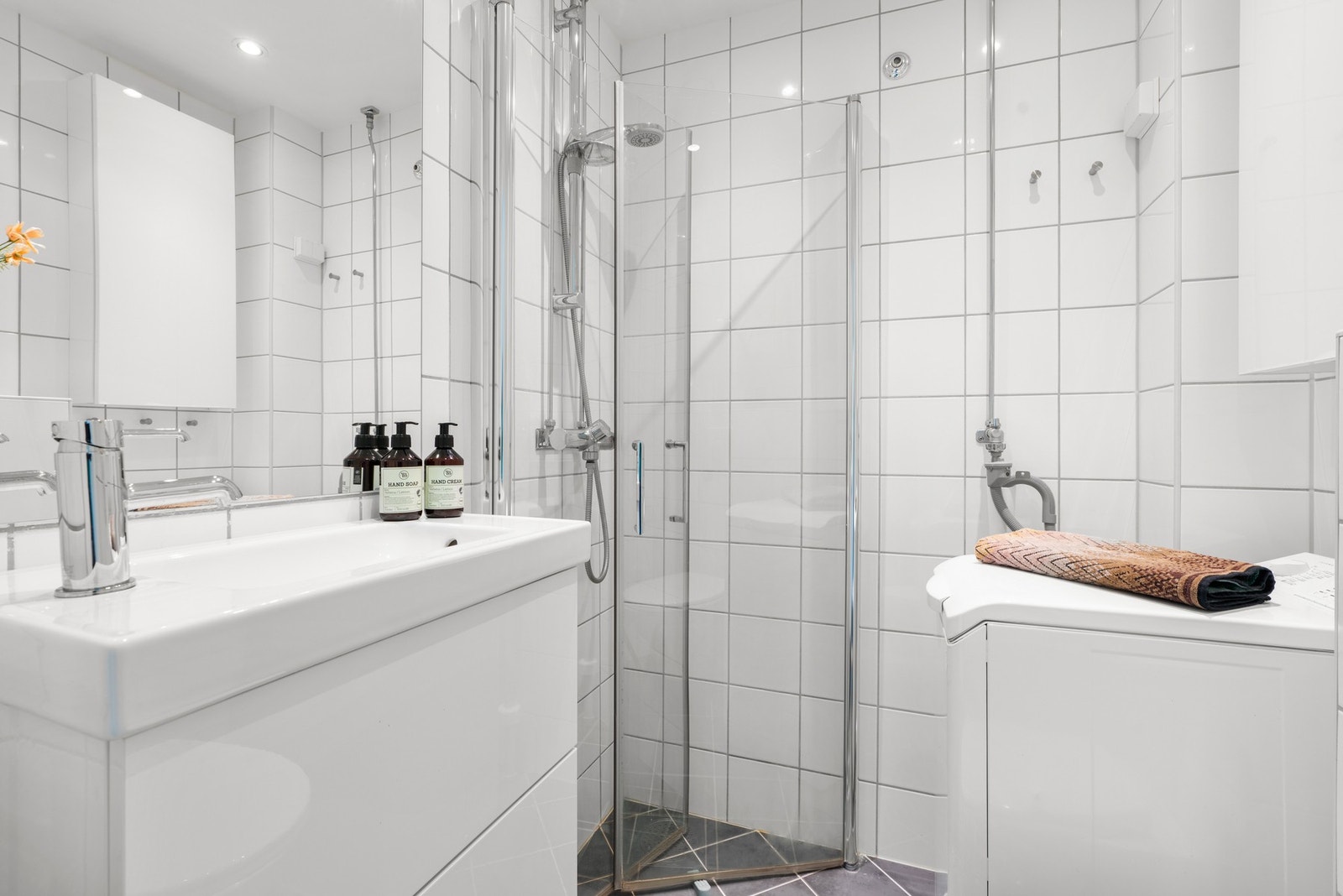Badet har varmekabler i gulvet, opplegg for vaskemaskin og downlights i himling. I hjørnet er det dusjnisje med innfellbare glassdører. Galleribilde