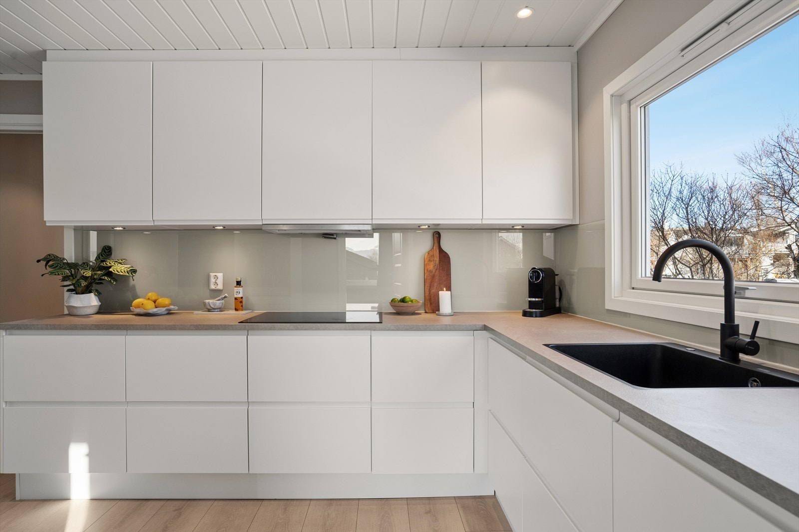 Det er rikelig med skap- og benkeplass, nedfelt sort kjøkkenvask, praktisk plasserte stikkontakter og downlights i både tak og under overskap Galleribilde