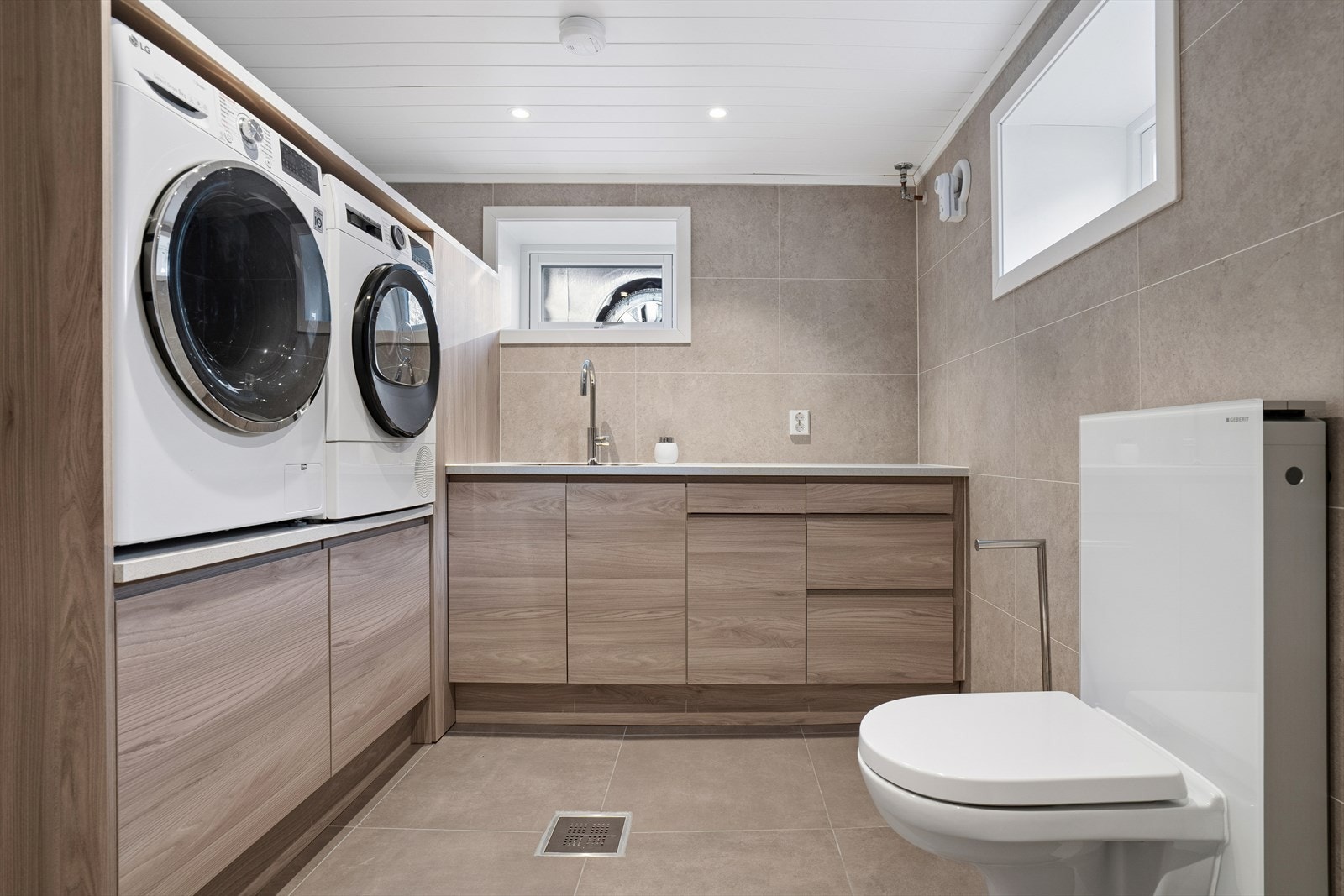 Praktisk innredning med utslagsvask, skuffer, skap og hylle for vaskemaskin/tørketrommel i ståhøyde - Rommet har også vegghengt toalett Galleribilde