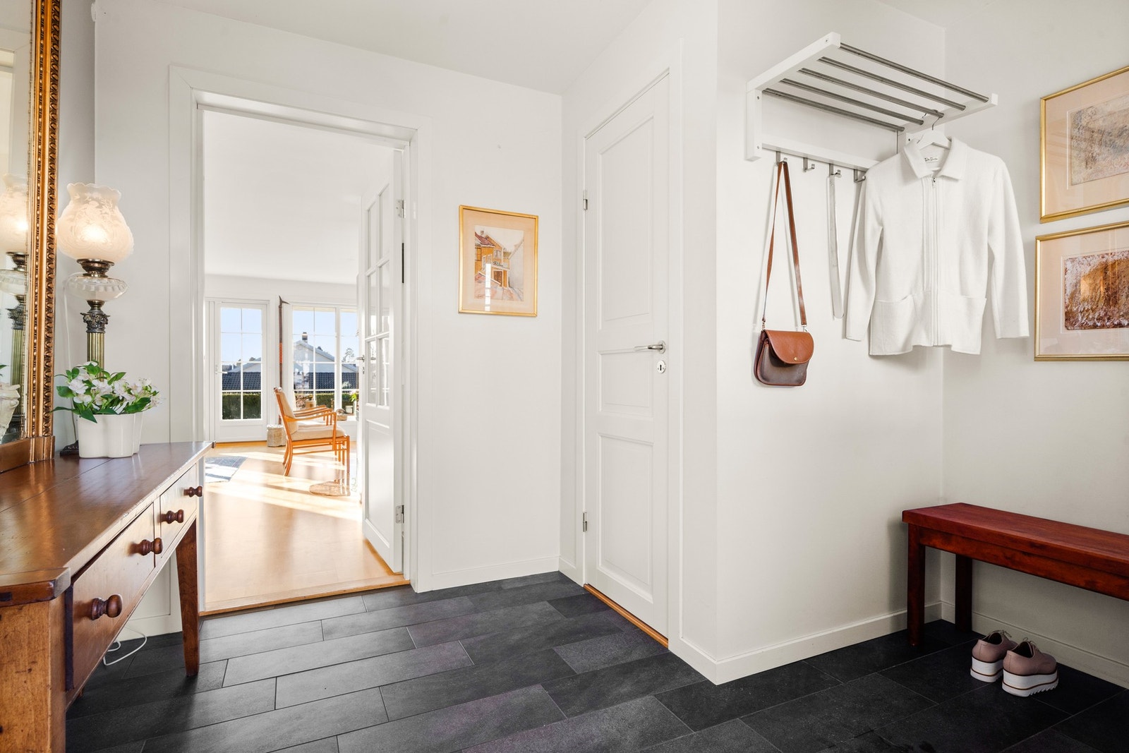 Romslig flislagt entré/gang med plass til klesoppheng og inngang til toalettrom Galleribilde