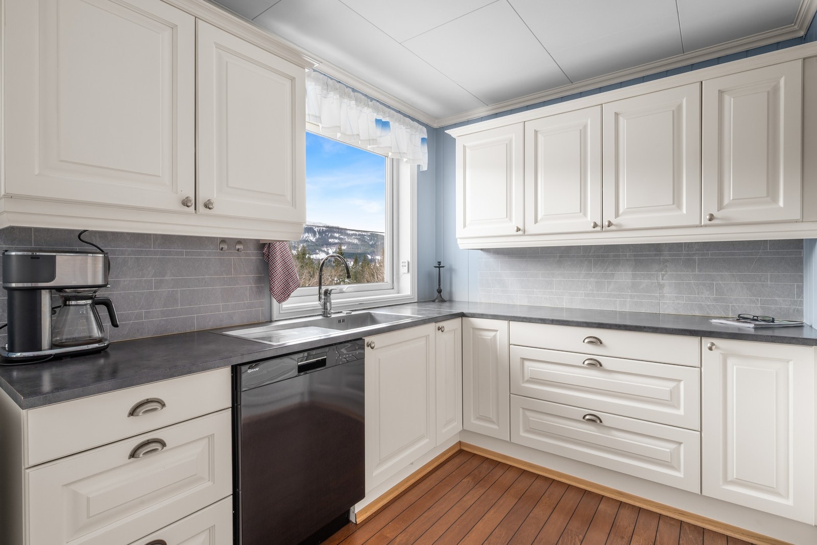 Kjøkkenet inneholder innredning med integrert stekeovn og platetopp, samt. opplegg for oppvaskmaskin. Galleribilde