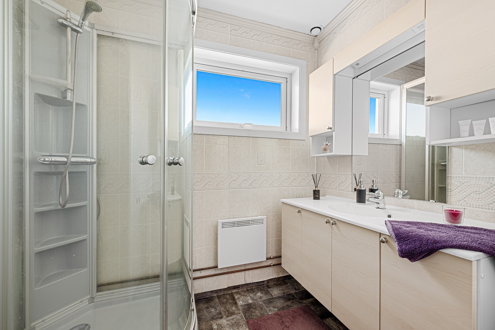 Bad med dusjkabinett og servant i romslig innredning Galleribilde