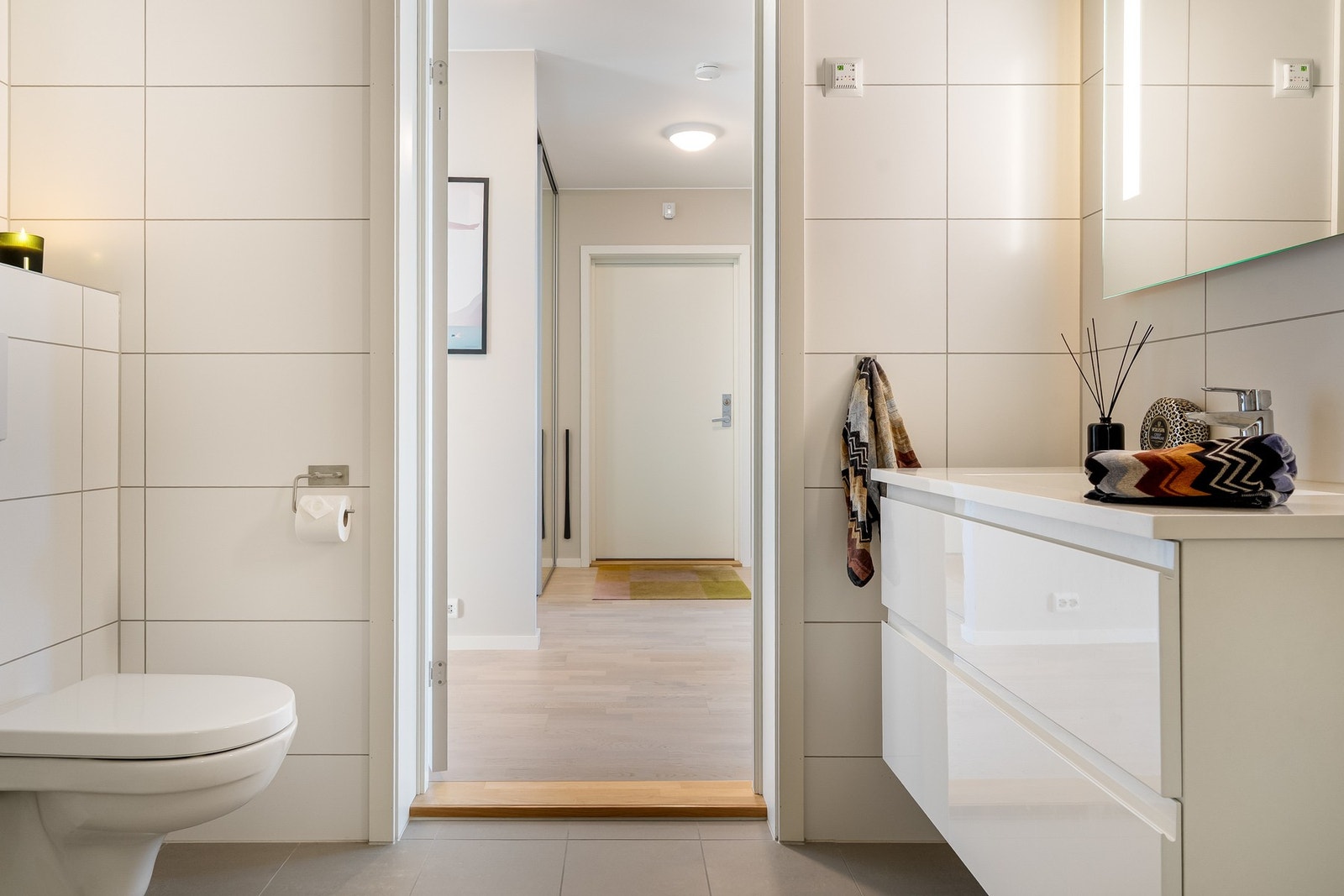 Badet har keramiske fliser og varme i gulvet. Rommet er innredet med servant med underskap, speil med belysning, toalett og dusjvegger i glass. Galleribilde