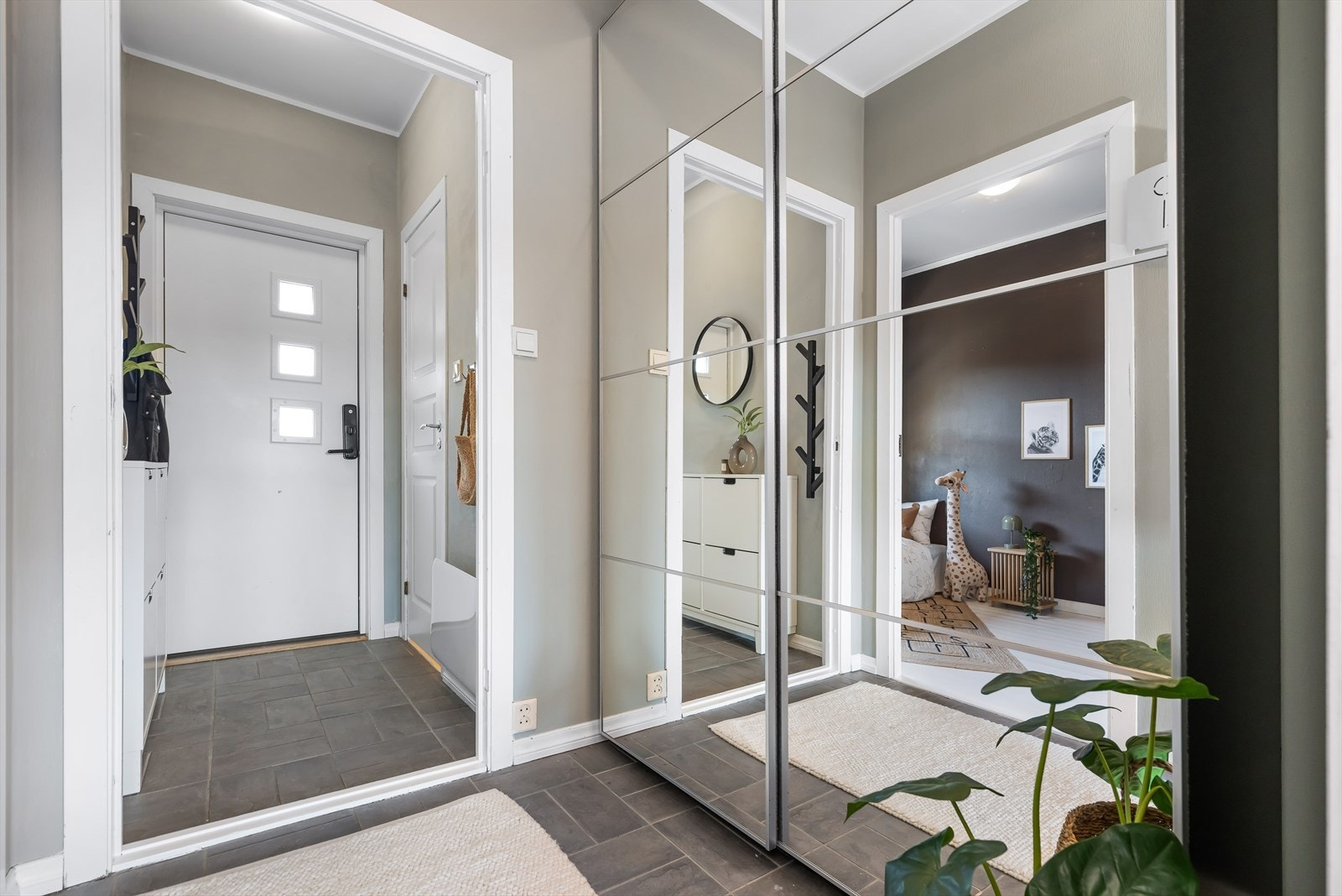 Innbydende og flislagt entré med skyvedørsgarderobe for oppbevaring av sko og yttertøy. Galleribilde