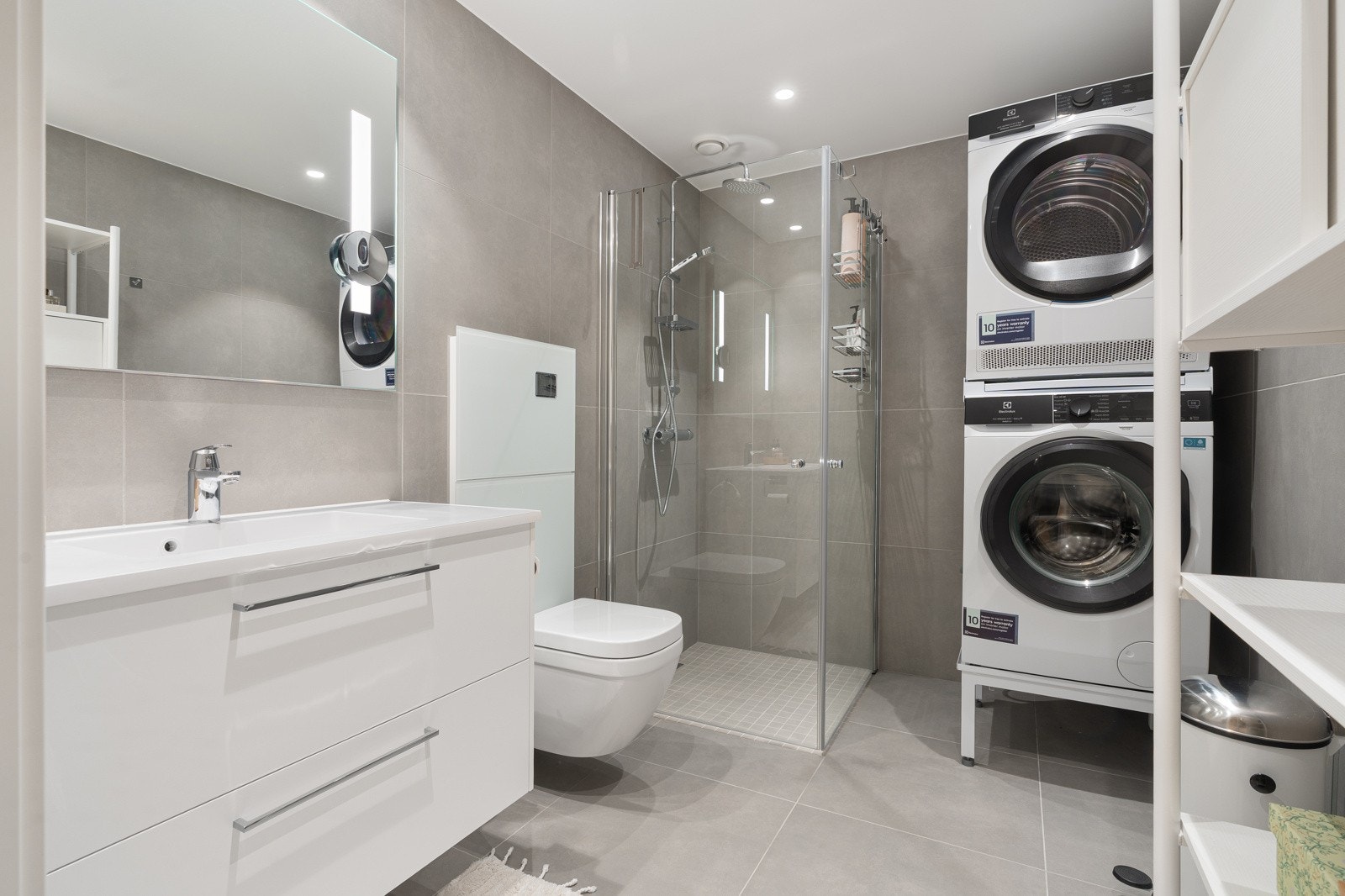 Lekkert bad med delikate 60x60 fliser. Badet er utstyrt med stor dusjhjørne, praktisk vegghengt toalett og plass for vaskemaskin/tørketrommel. Galleribilde