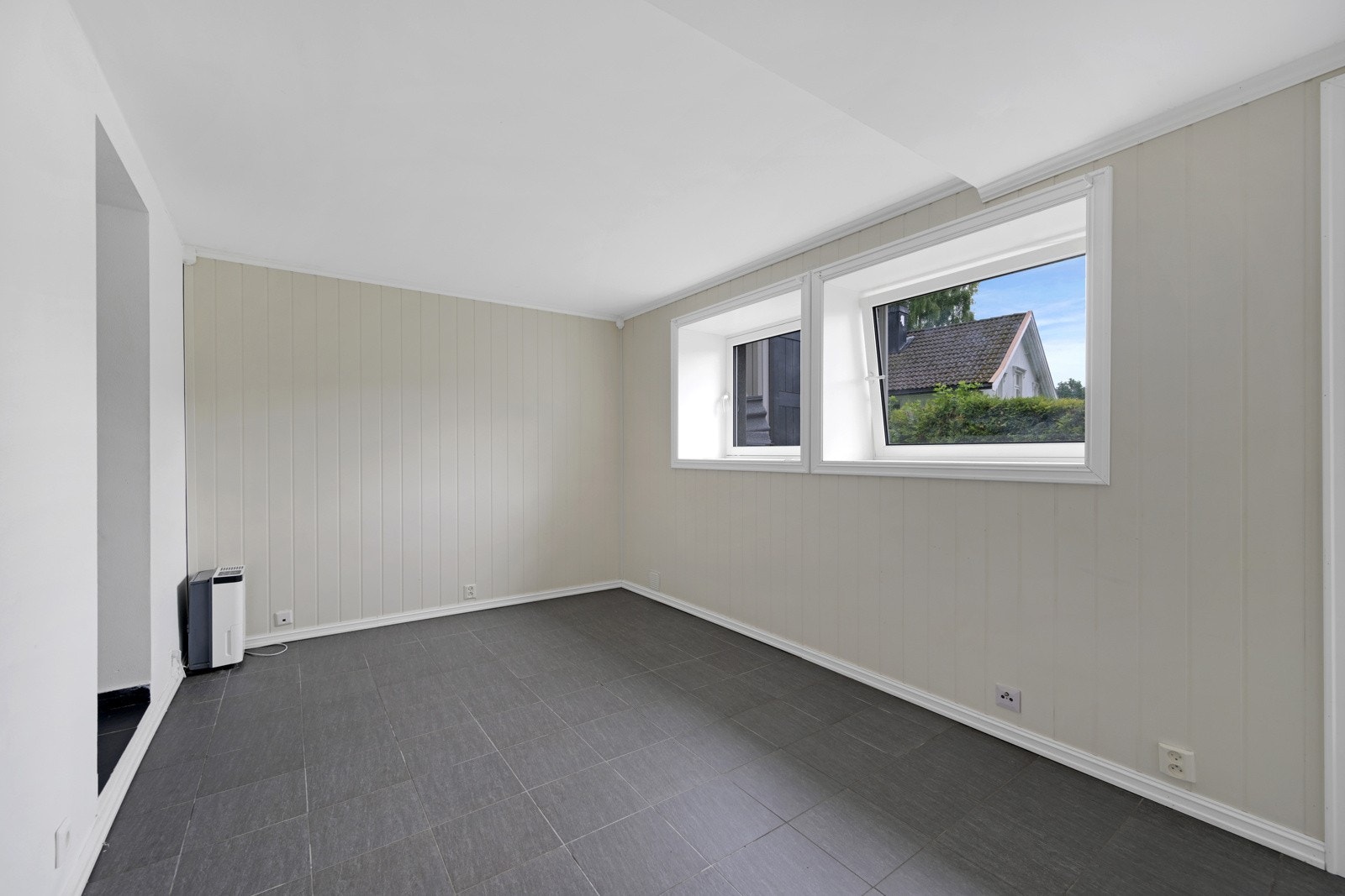 Det er en stue i underetasjen som får godt med naturlig lys igjennom vinduene Galleribilde