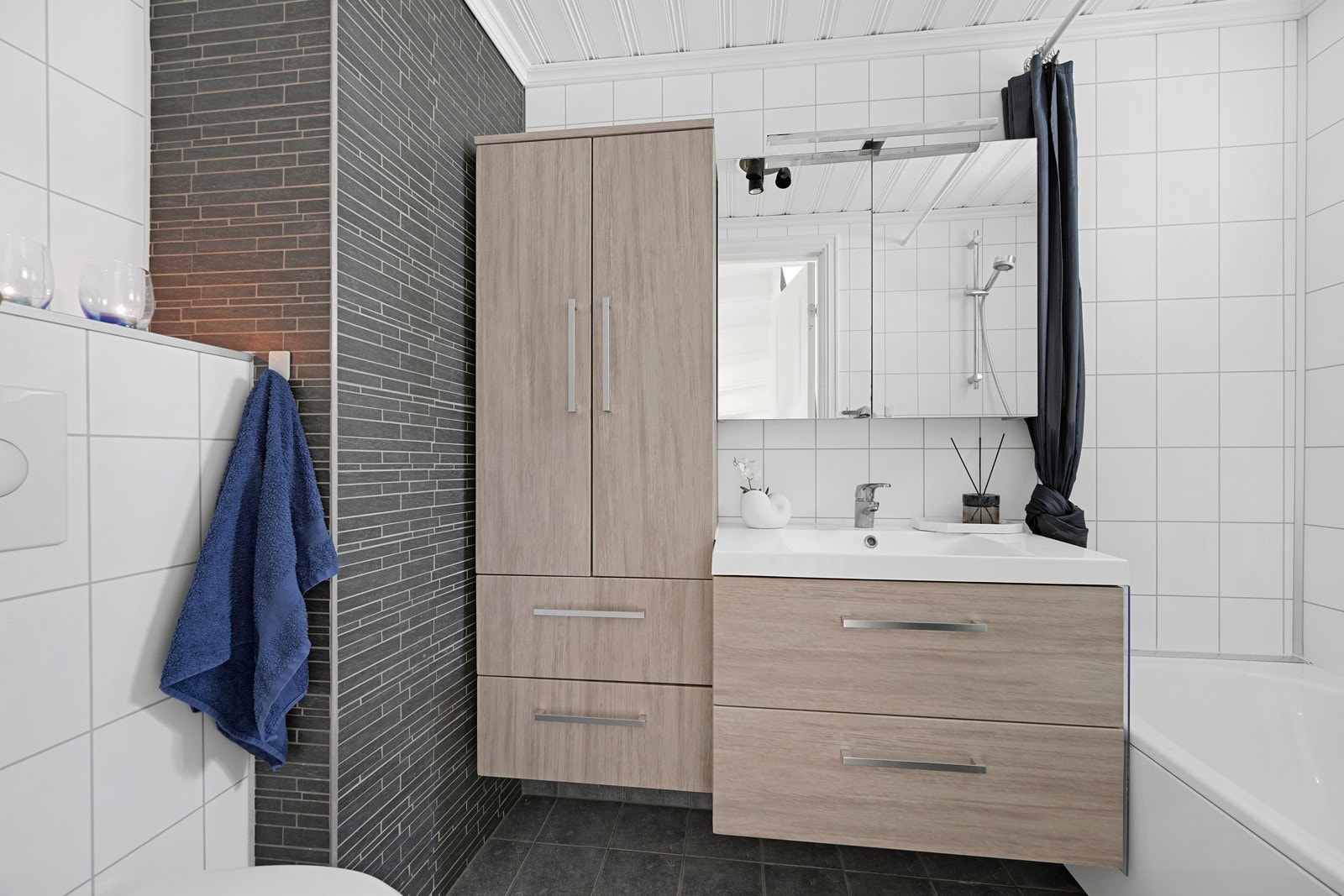 Lekkert flislagt bad i 1. etasje med et badekar, samt romslig innredning med plass til det en trenger Galleribilde