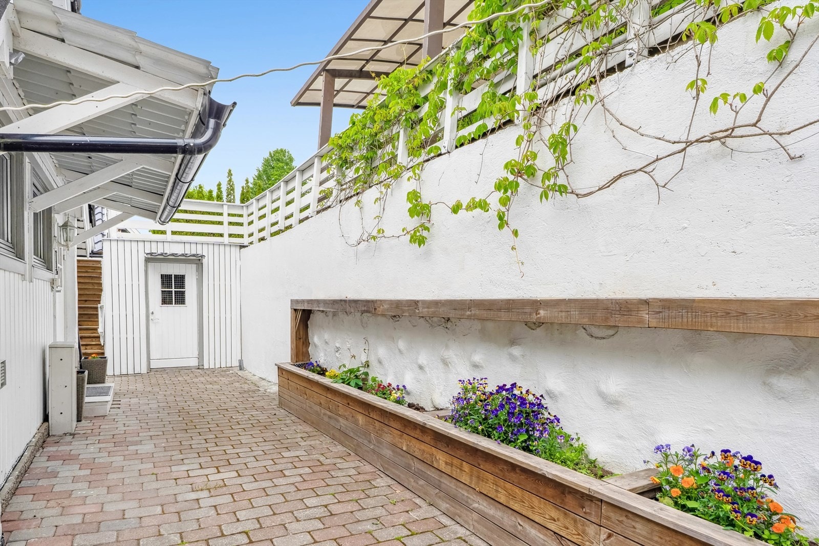 Hyggelig, inngangsparti med belegningssten og blomsterkasser. Galleribilde