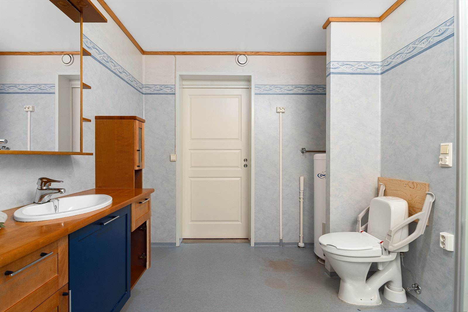 Badet har innredning med servant nedfelt i benkeplate over benkeskap, veggskap, speil og toalett. Galleribilde