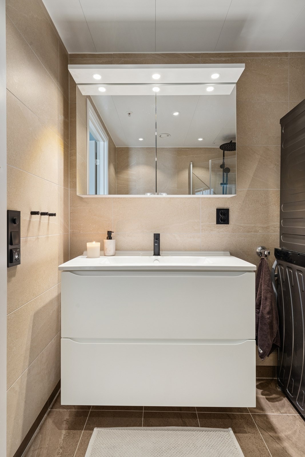 Baderommet med flislagte vegger og gulv i morderne og tidløse farger. Rommet varmes opp med elektriske varmekabler. Galleribilde