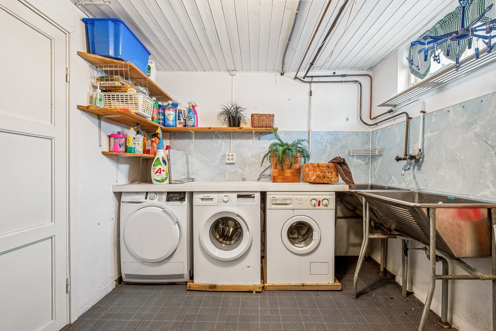 Praktisk vaskekjeller med betonggulv, to rustfrie vaskekar og opplegg for vaskemaskin. Galleribilde