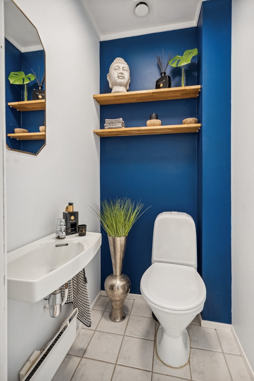 Toalettrommet har flislagt gulv, tapetserte vegger og er innredet med servant og toalett. Den blå veggen er malt siden bilder (nå samme som på hovedsoverommet). Galleribilde