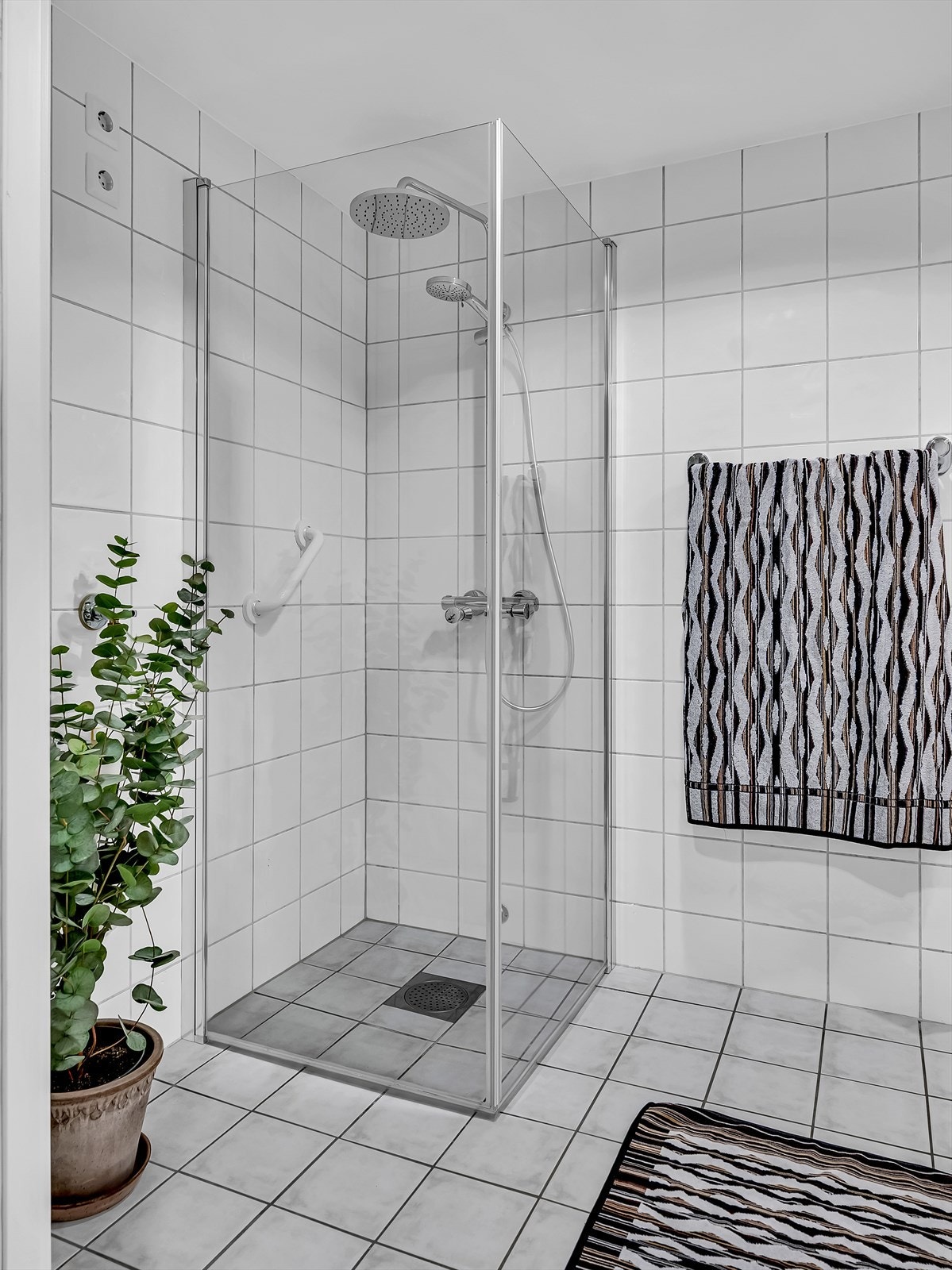 Baderommet har plastsluk med synlig mansjett, vegghengt toalett, opplegg for vaskemaskin og dusjhjørne med glassdører. Galleribilde