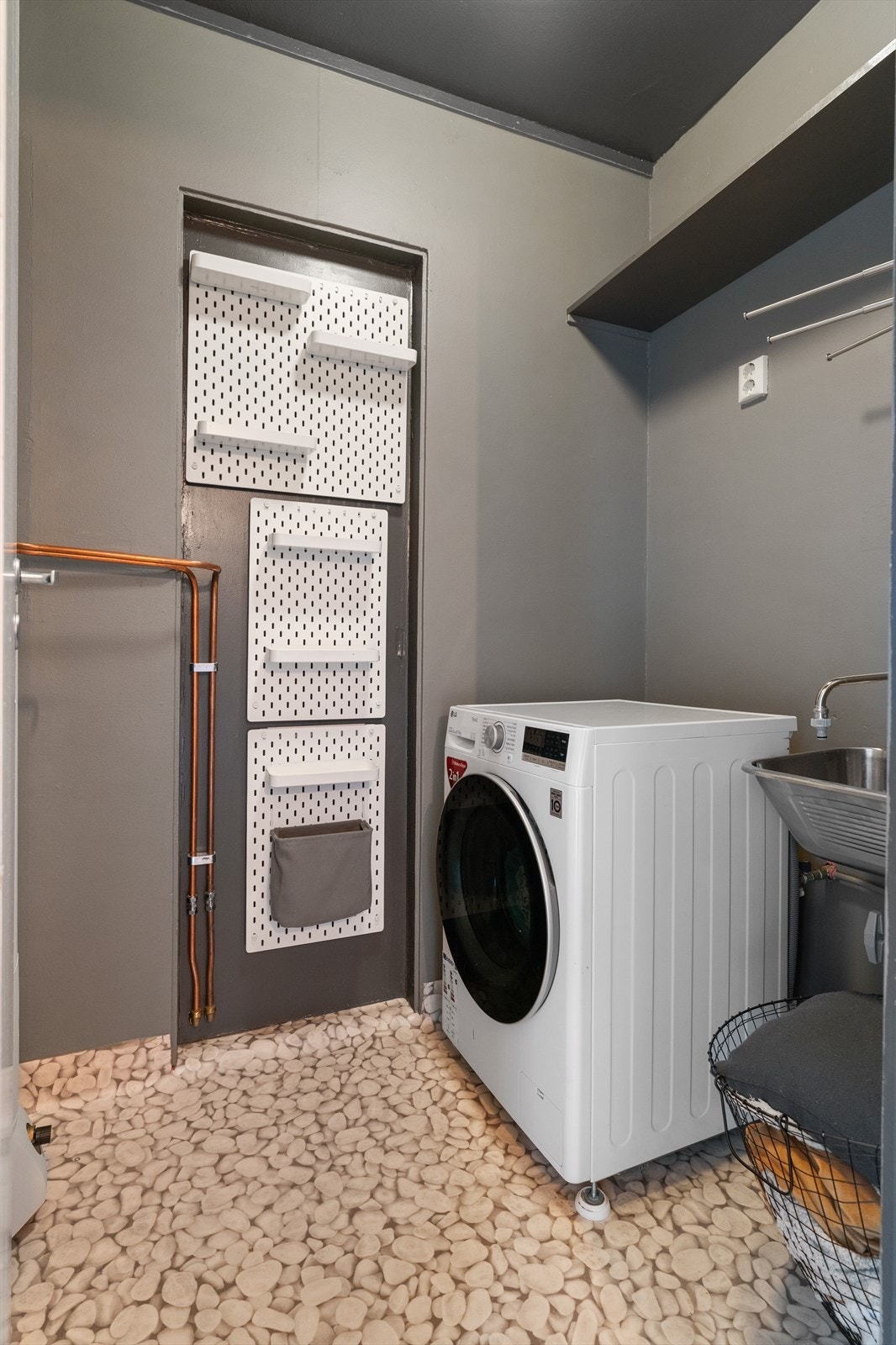 Praktisk vaskerom med vegghengt utslagsvask, uttak for vaskemaskin/tørketrommel og varmtvannsbereder Galleribilde