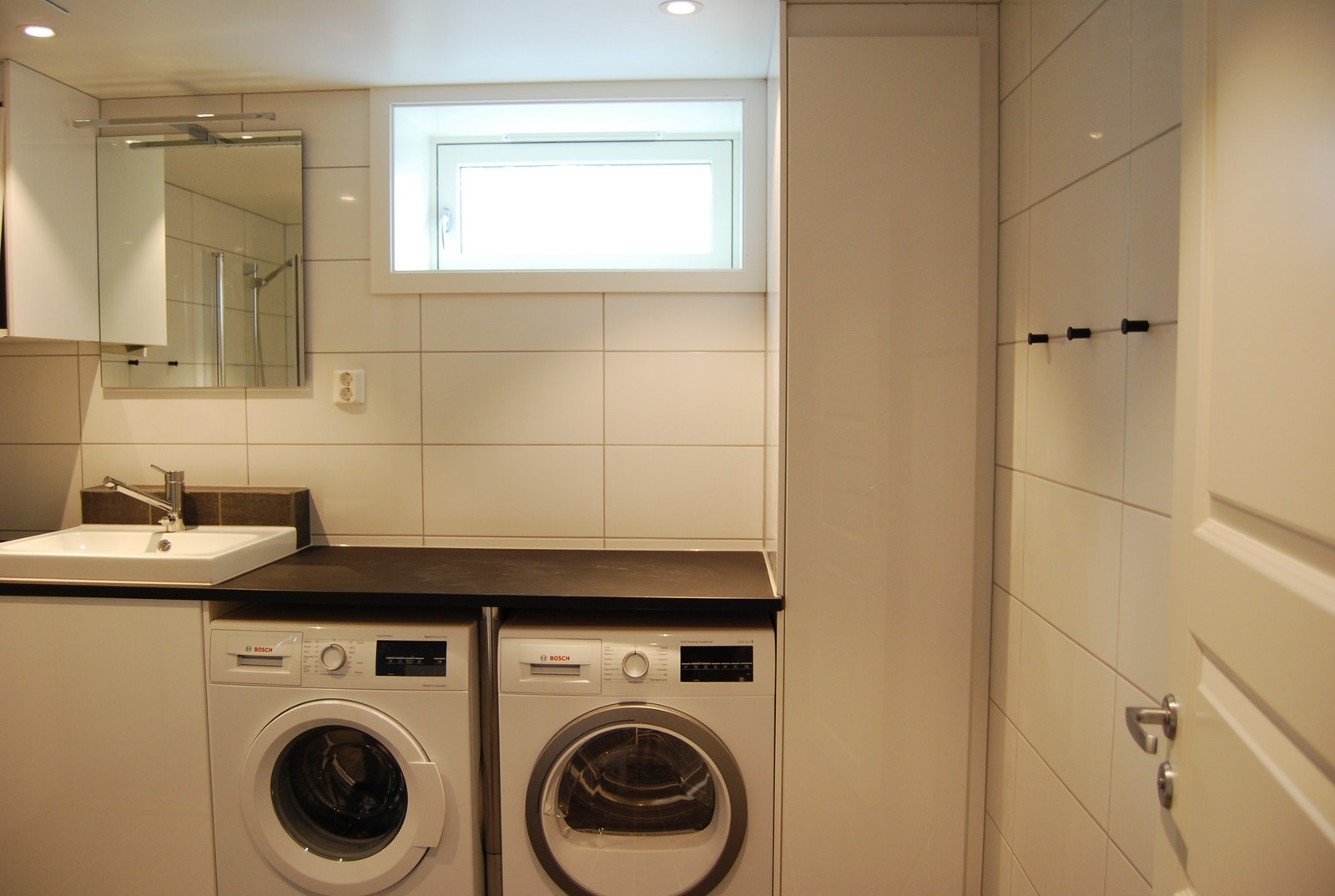 Bad med servantskap, høyskap, dusjnisje, vegghengt wc, vaskemaskin og tørketrommel. Galleribilde