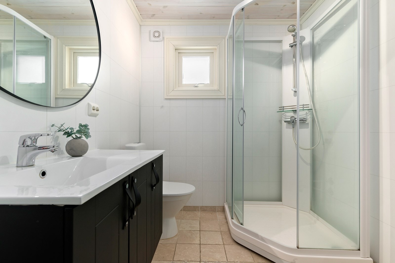 Badet har fliser på gulvet, våtromsplater på vegg og mekanisk avtrekk. Innredet med wc, servant med oppbevaring og dusjkabinett. Galleribilde