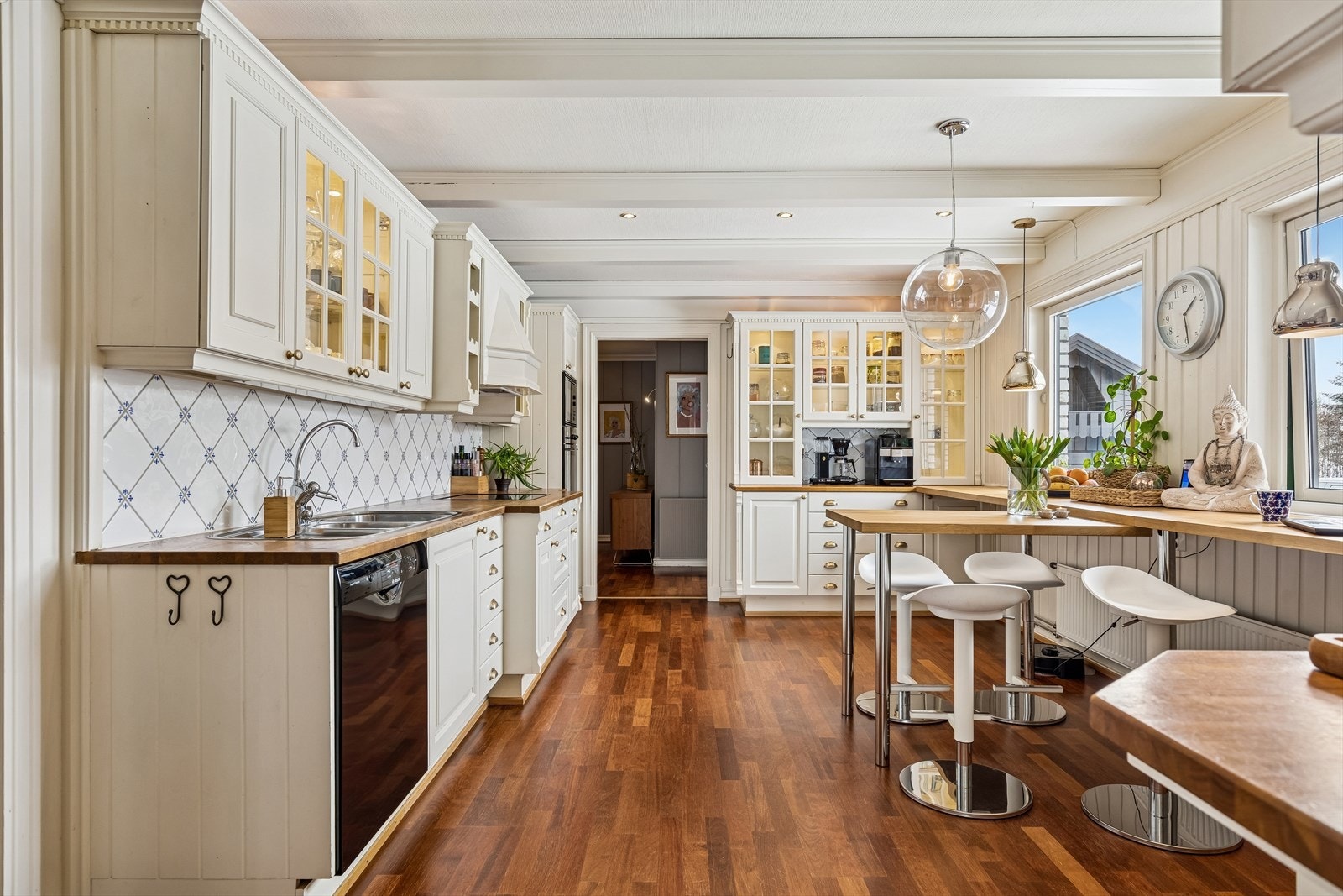 Kjøkkenet har møbelsnekret heltre innredning med profilerte fronter, ventilatorhette over kokeplass og benk med eikefinert plate og metallbein. Galleribilde