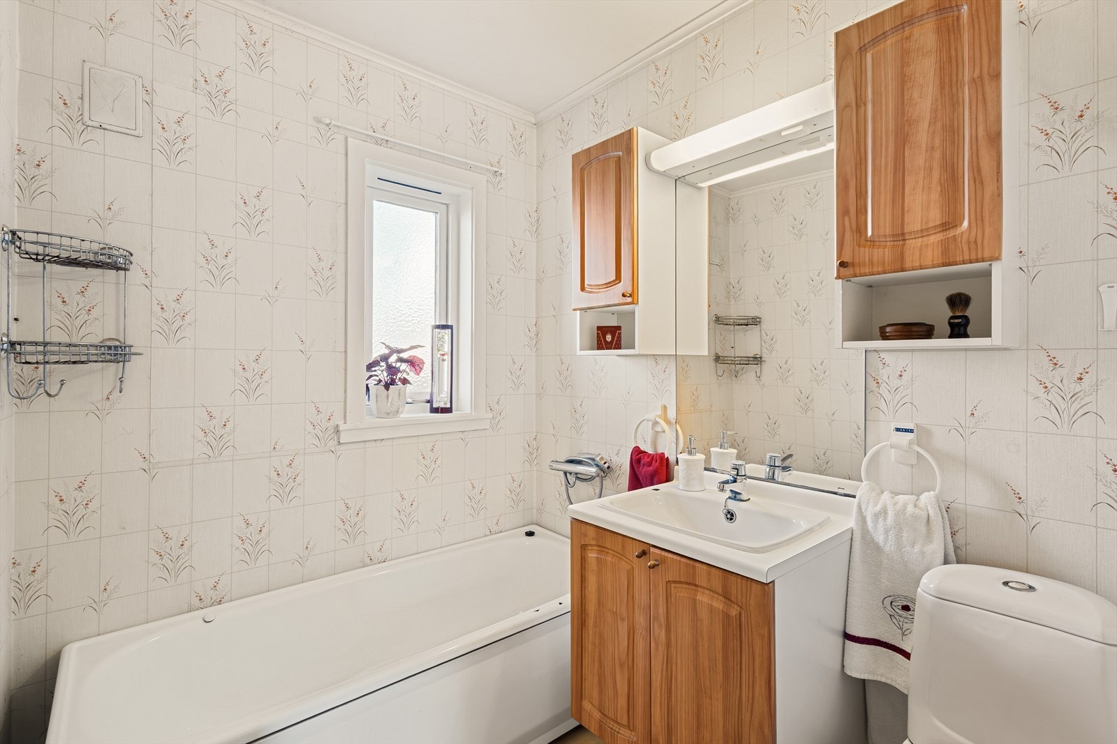 Bad i 1. etasje har tapet på vegger, malt himling og vinylbelegg på gulv med elektriske varmekabler. Galleribilde