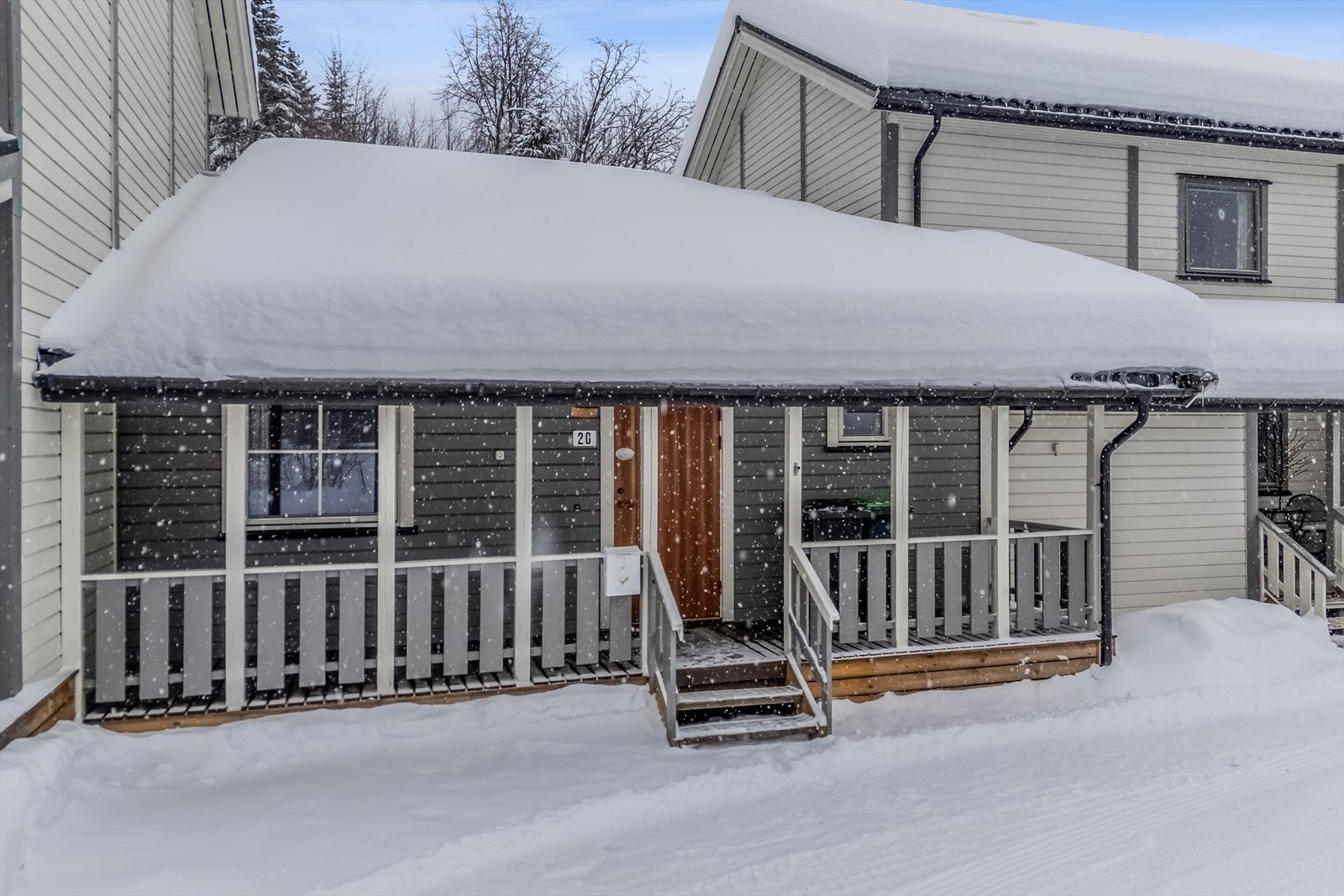 Inngangspartiet har en tretrapp med strekkmetall i trinn, og fasaden er kledd med liggende bordkledning. Galleribilde