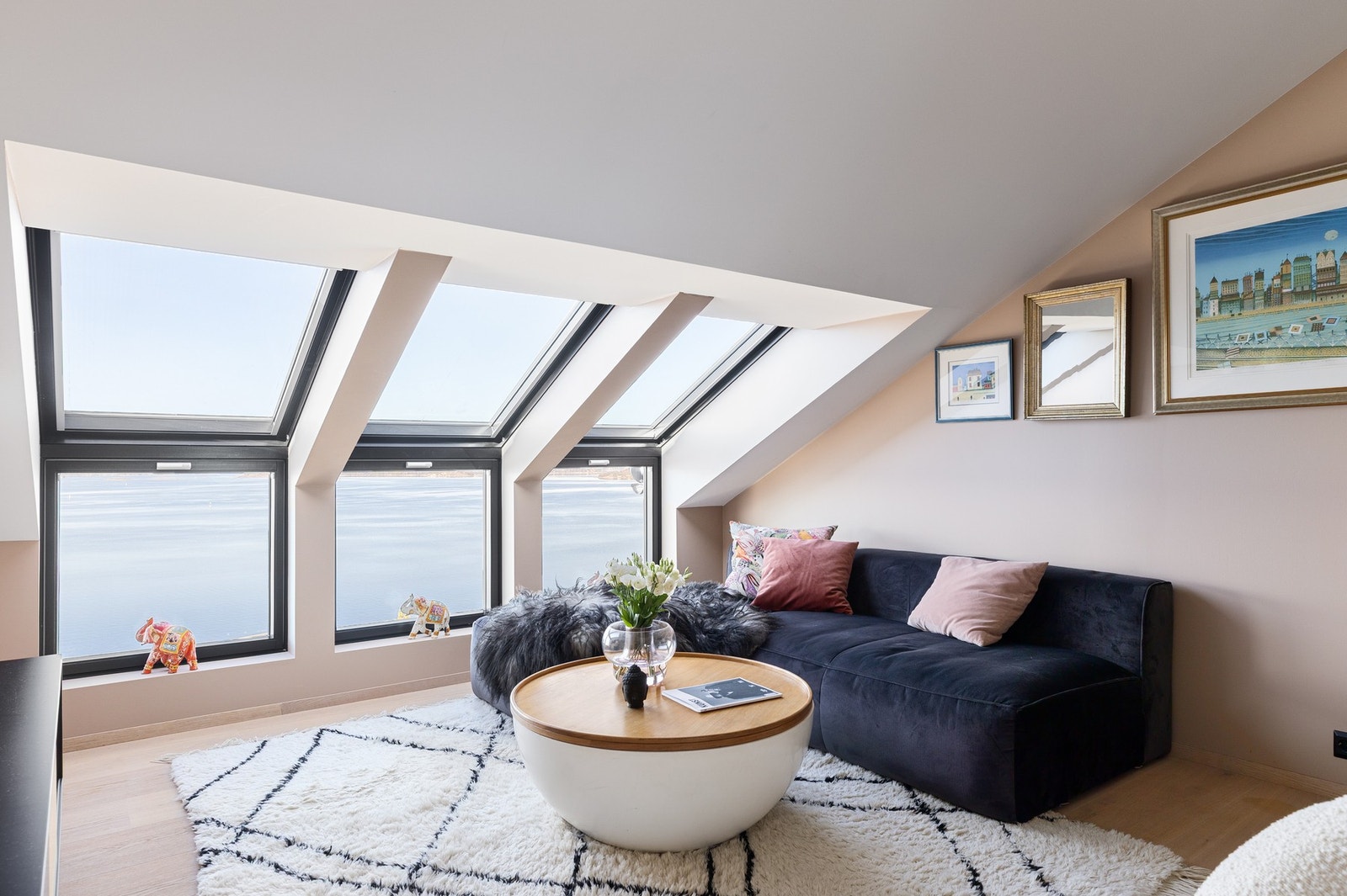 I boligens 2. etasje finner du en innbydende og sjarmerende loftsstue med store takvinduer som slipper inn rikelig med dagslys og rammer inn en spektakulær utsikt over sjøen. Galleribilde