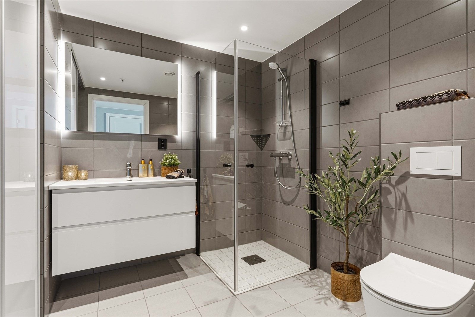 Lekkert, flislagt baderom som sørger for en god start på dagen! Badet er oppgradert med større møblement og dusjdører med sorte detaljer. Galleribilde