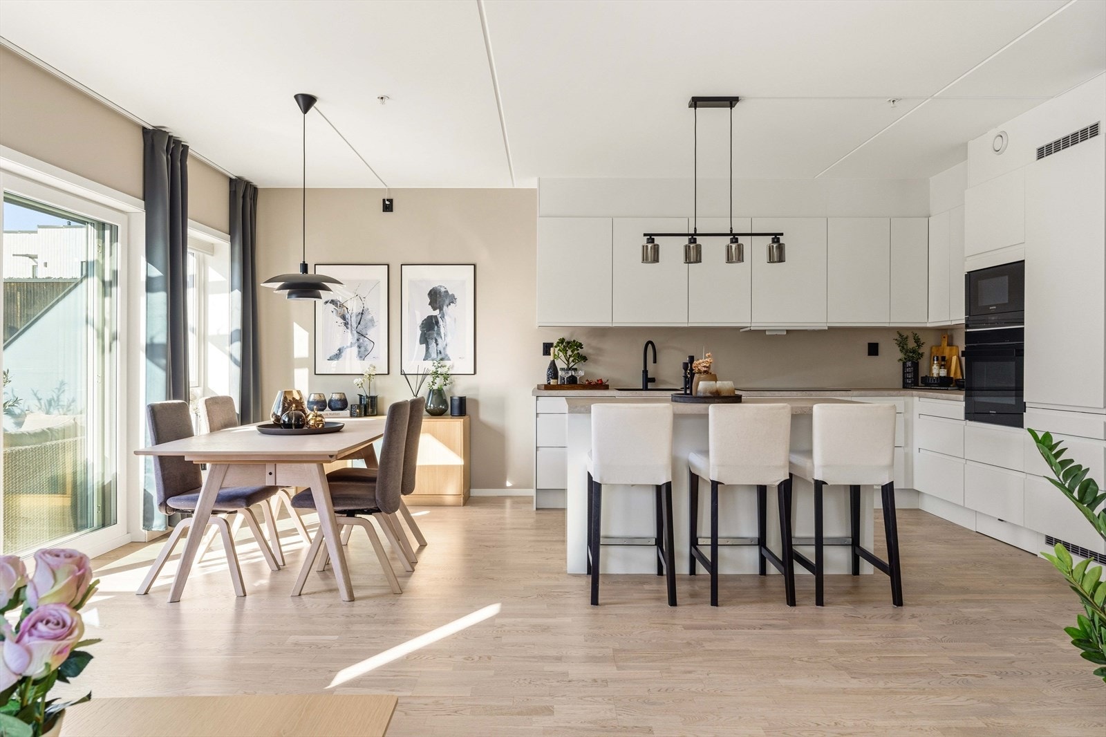 Den åpne planløsningen gir en naturlig flyt mellom kjøkken og spiseplass. Store vindusflater slipper inn rikelig med dagslys og skaper en innbydende atmosfære. Galleribilde