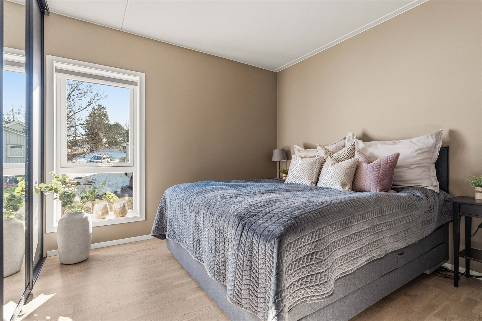 Romslig hovedsoverom med store vinduer og behagelig fargepalett. Et rolig og komfortabelt rom for hvile og avslapning. Galleribilde