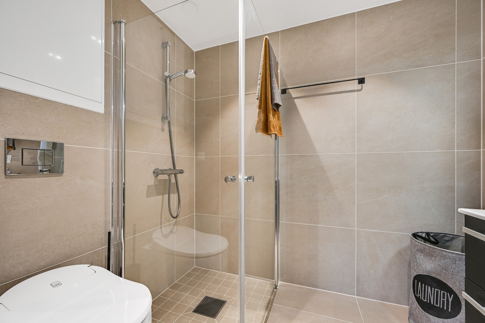 Badet er innredet med pene og praktiske dusjvegger, vegghengt spyletoalett og pen baderomsinnredning Galleribilde