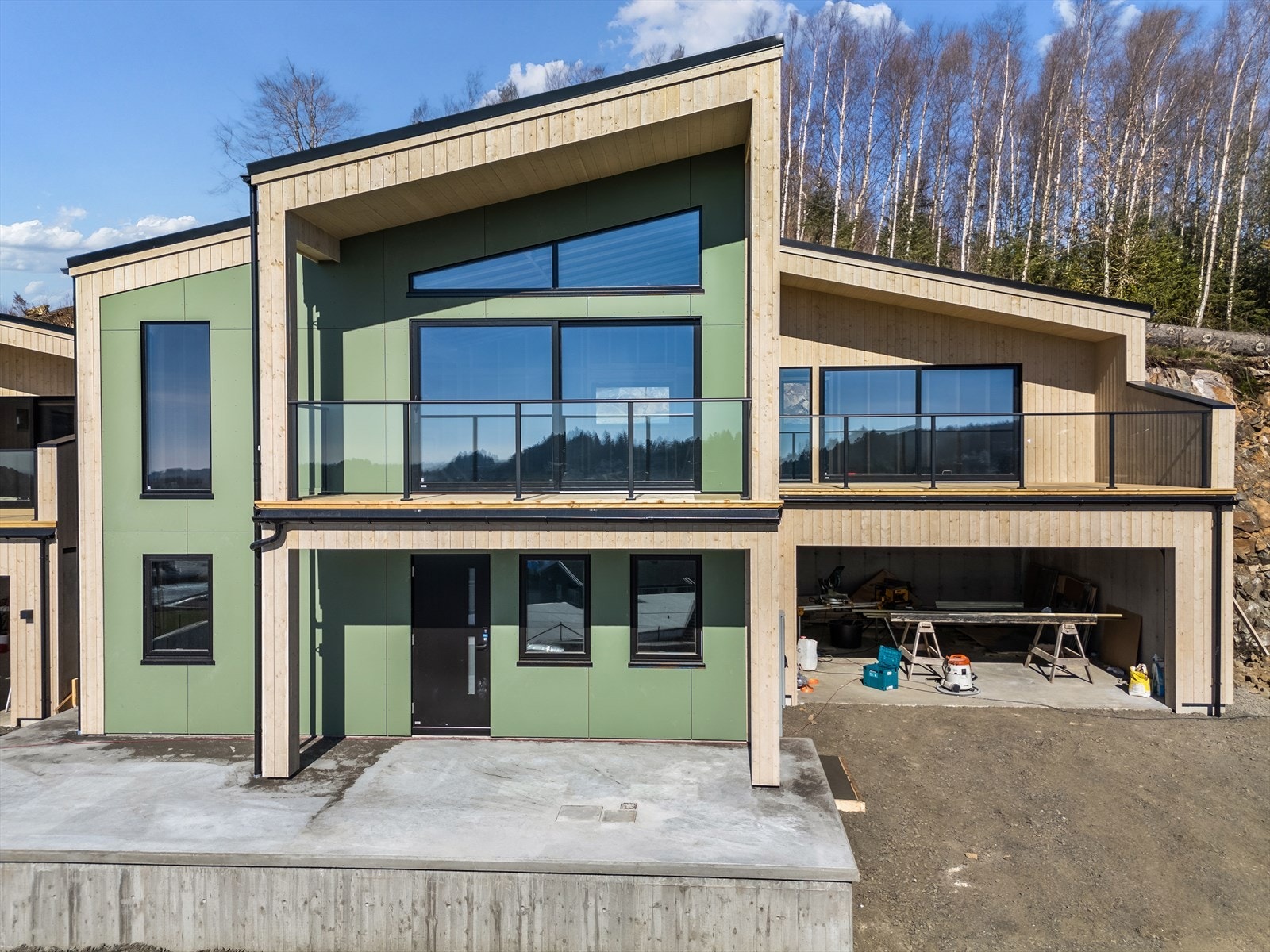 Boligen har et moderne uttykk med steniplater i grønt og beiset kledning. Galleribilde