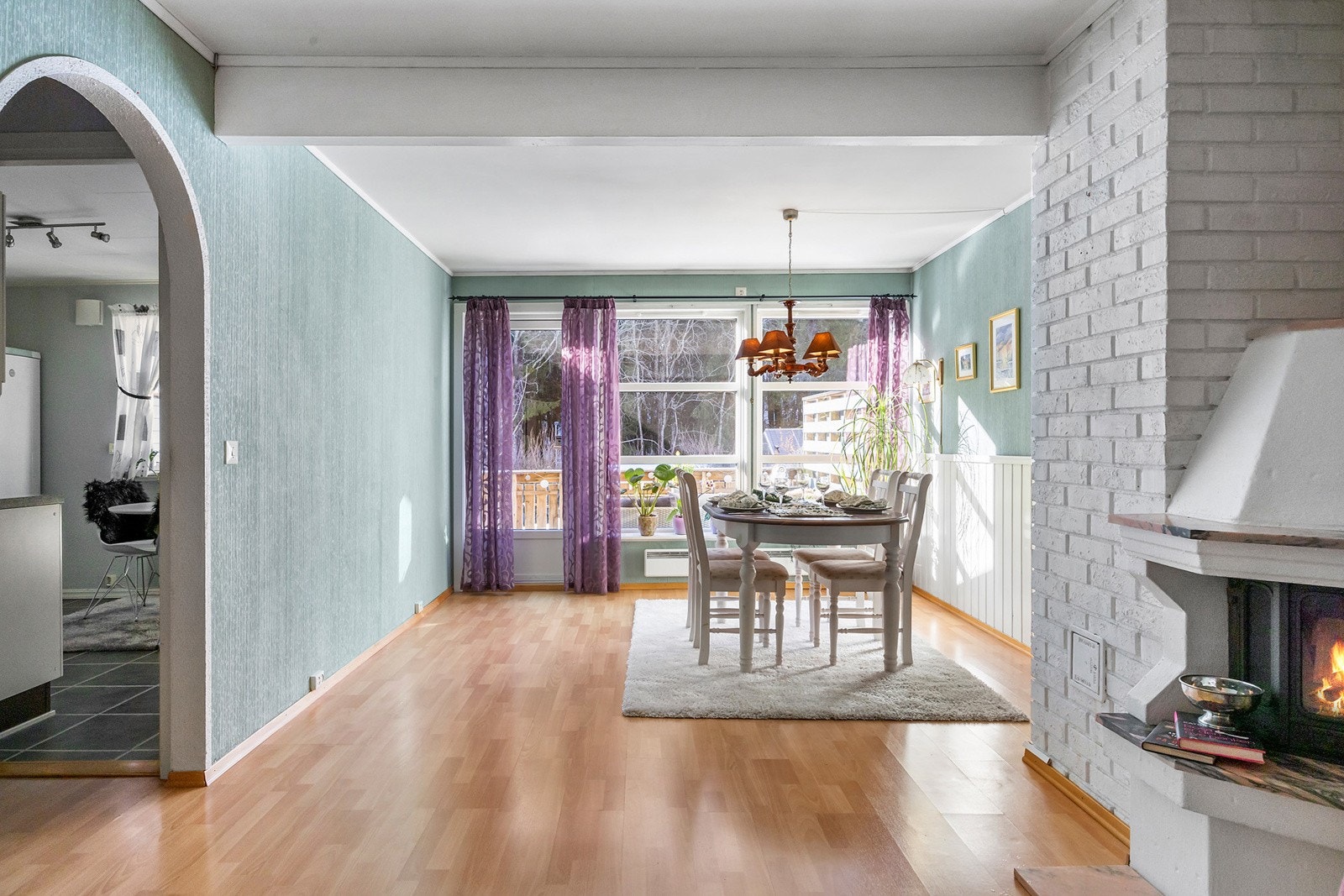 Lys og åpen stue med peis og utgang til boligens vestvendte terrasse Galleribilde