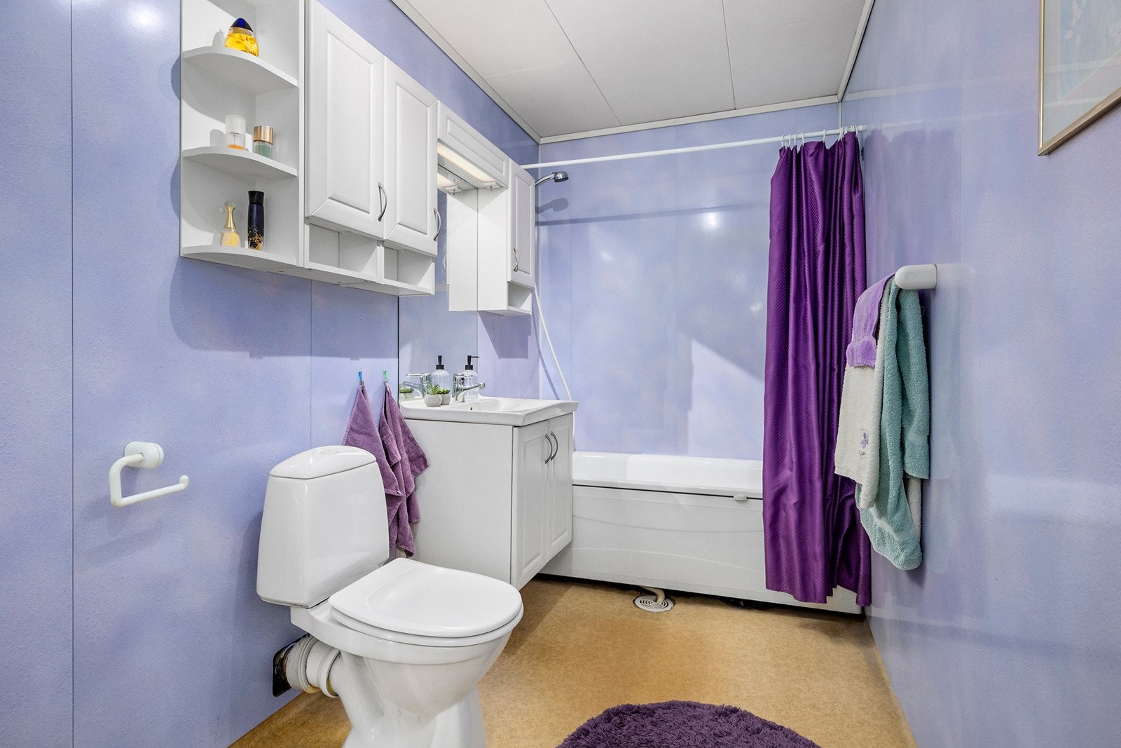 Romslig bad med badekar, servant med speil og skapløsning og gulvmontert toalett Galleribilde