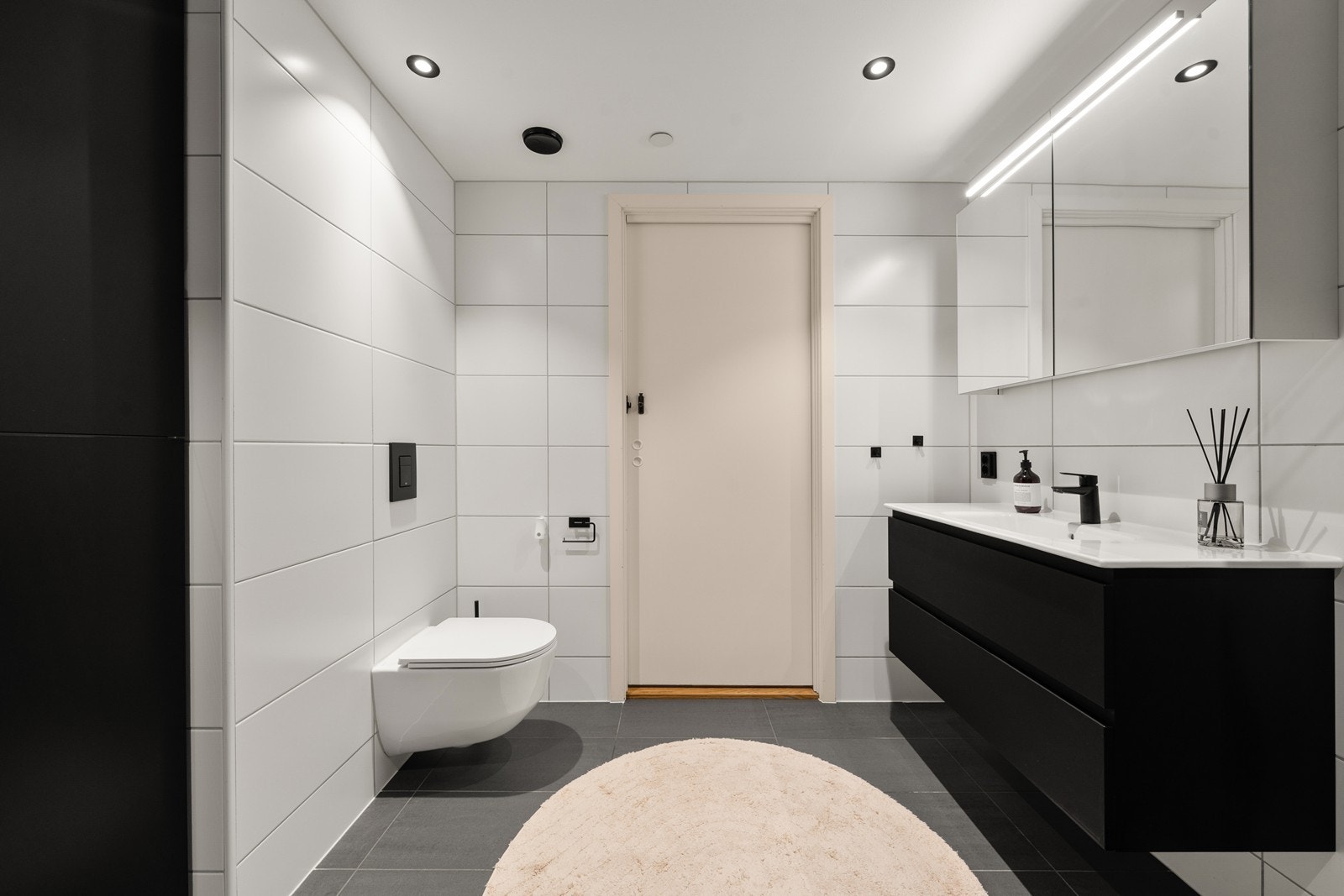 Badet er innredet med vegghengt toalett, helservant på skuffeseksjon, dusjhjørne og opplegg for vaskemaskin. Galleribilde