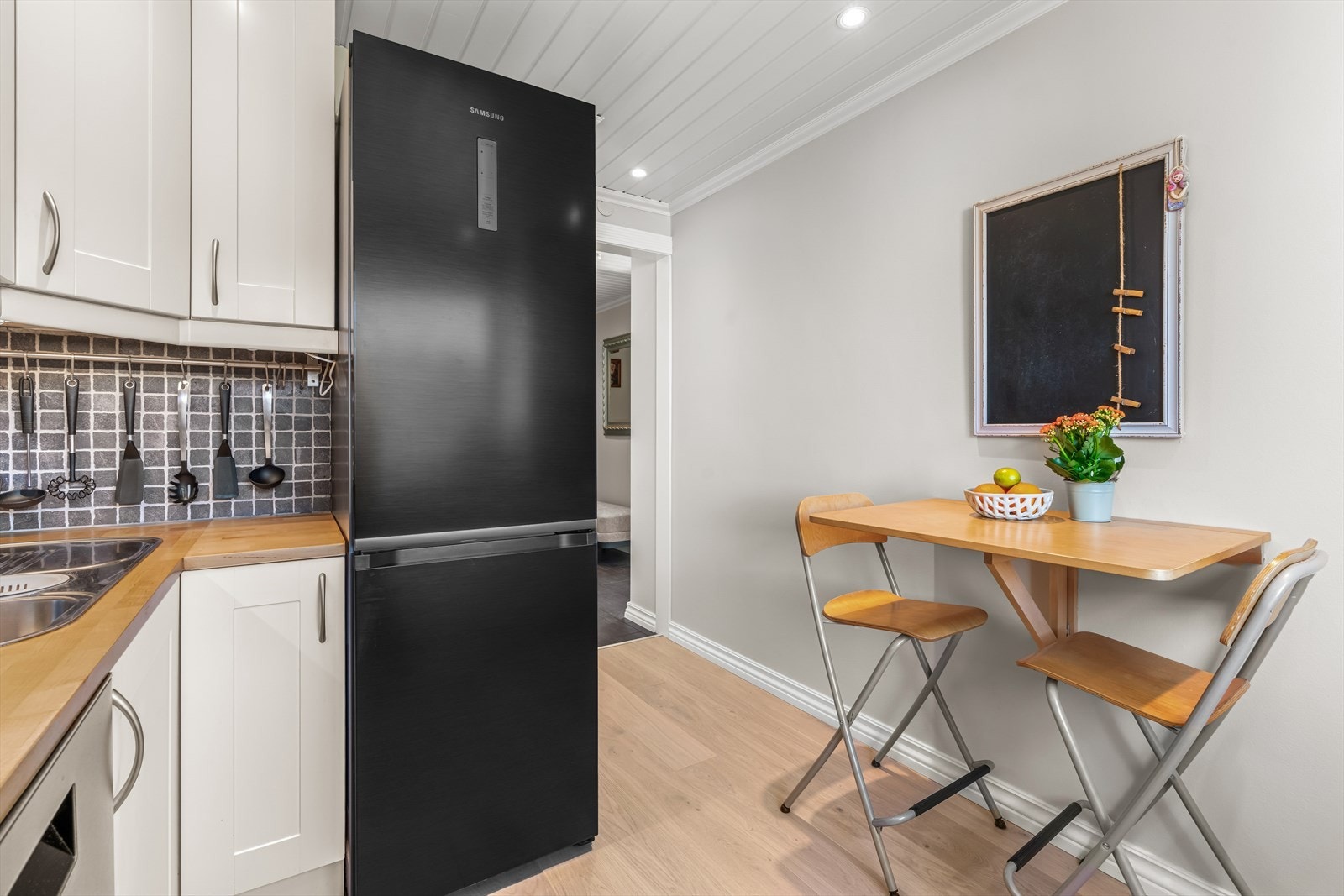 Det er flislagt mellom over- og underskap, og praktisk belysning er montert under overskapene. Galleribilde