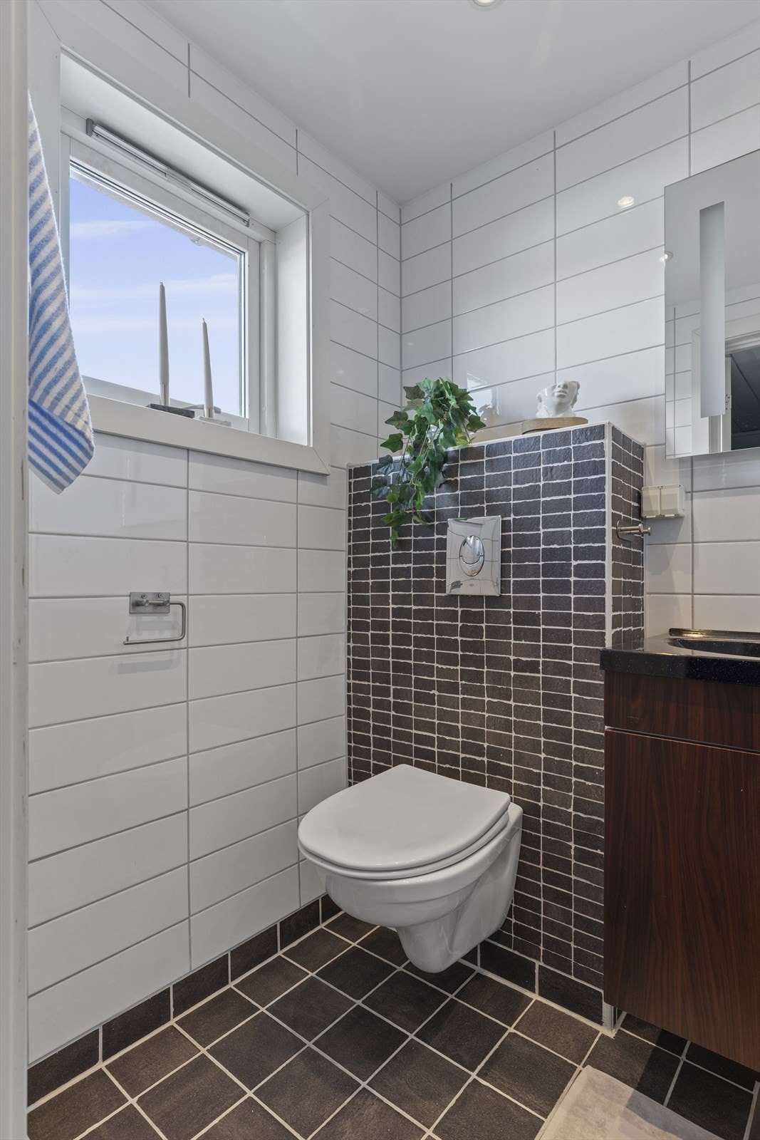 Speil med lys over servant. Vegghengt toalett. Senket og malt platehimling med LED belysning fra 2026. Plastsluk (hovedsluk) under baderomsmøbel og hjelpesluk i dusjhjørne. Galleribilde