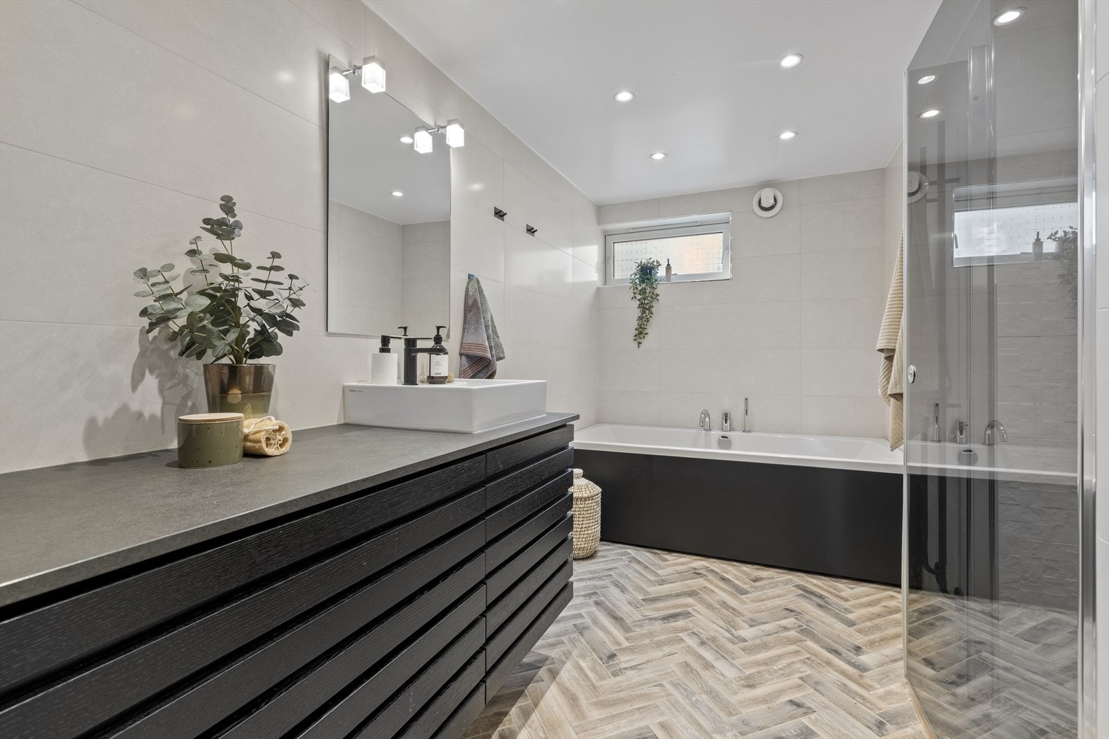 Pent flislagt bad/wc fra 2018 med badekar og dusjnisje med dør i herdet glass. Senket og malt platehimling med LED belysning. Varmekabler. Galleribilde