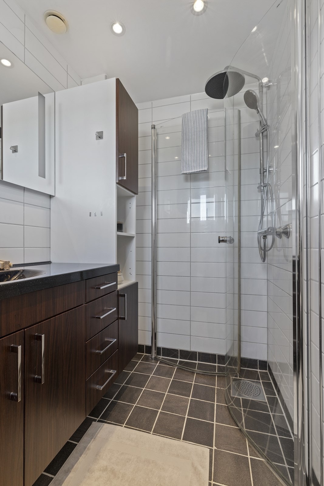 Flislagt bad/wc med dusjhjørne med dører i herdet glass. Regn og hånddusj. Heldekkende servant med underskap/skuffer. Galleribilde