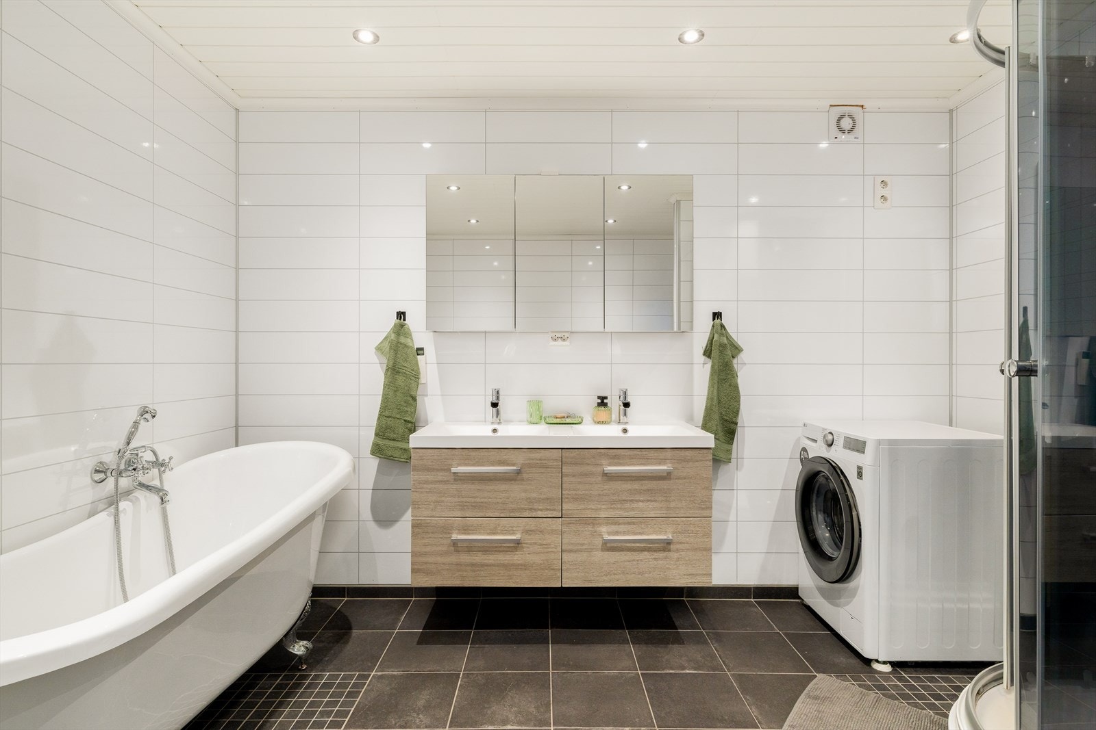 Stort flislagt baderom med varmekabler. Badet er innredet bade med badekar og dusjkabinett. Galleribilde