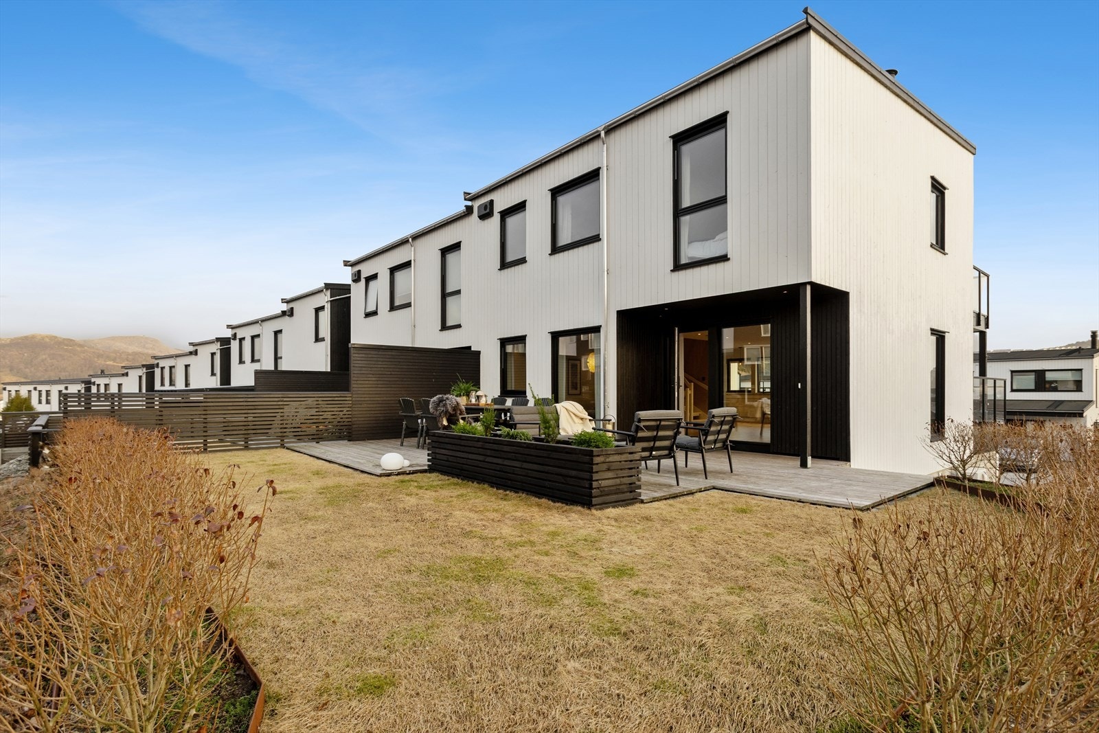 Uteareal byr på solrik terrasse og hage omringet av hekk Galleribilde