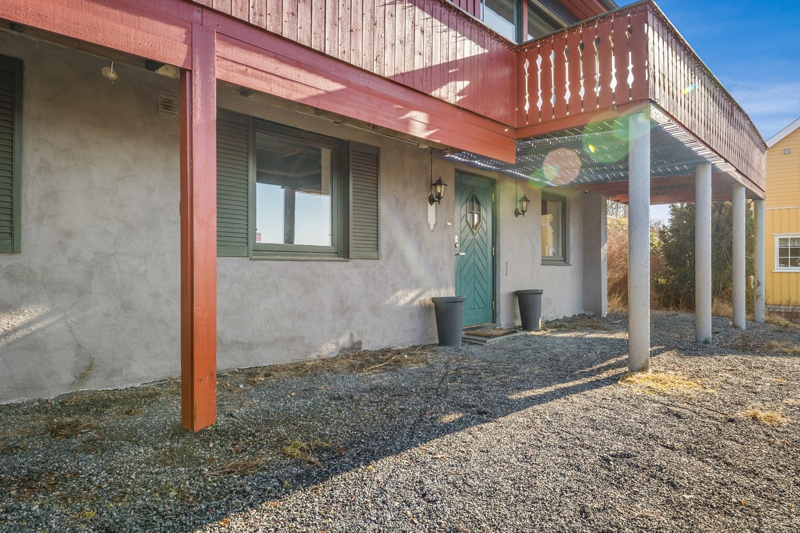 Overbygget inngangsparti i underetasjen med malt inngangsdør med glassfelt. Galleribilde