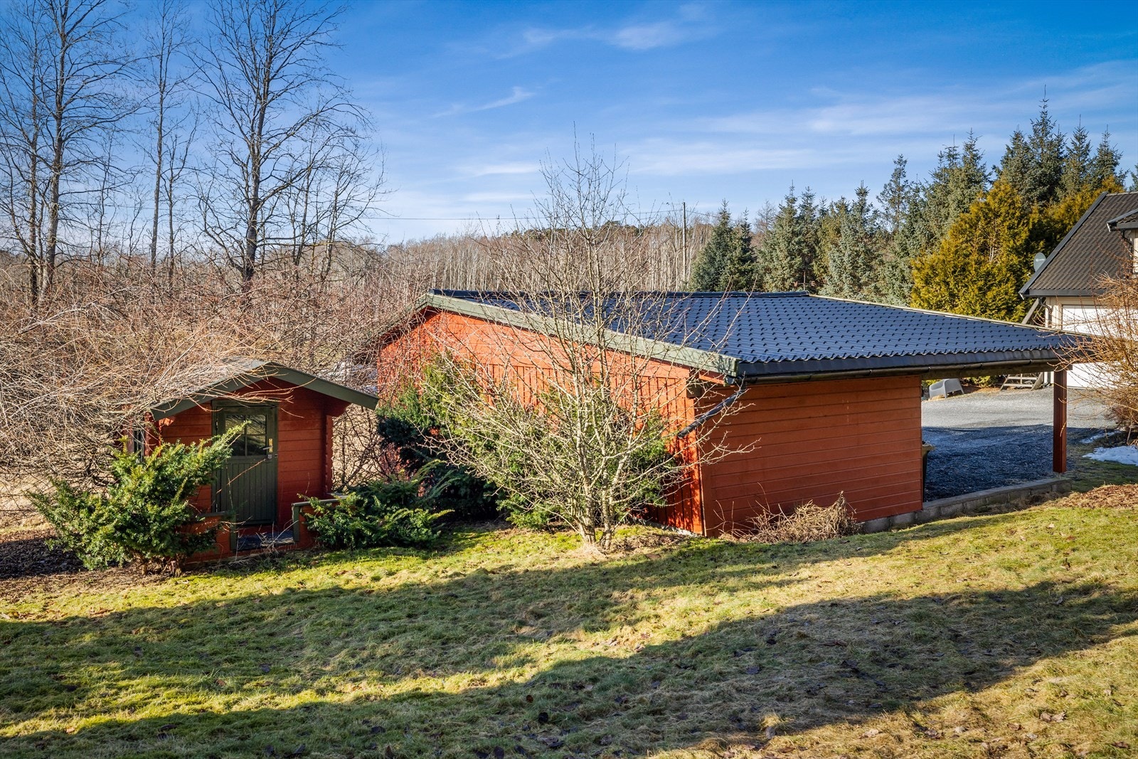 Garasjen har yttervegger av stående trekledning og saltak tekket med stålplater. Galleribilde