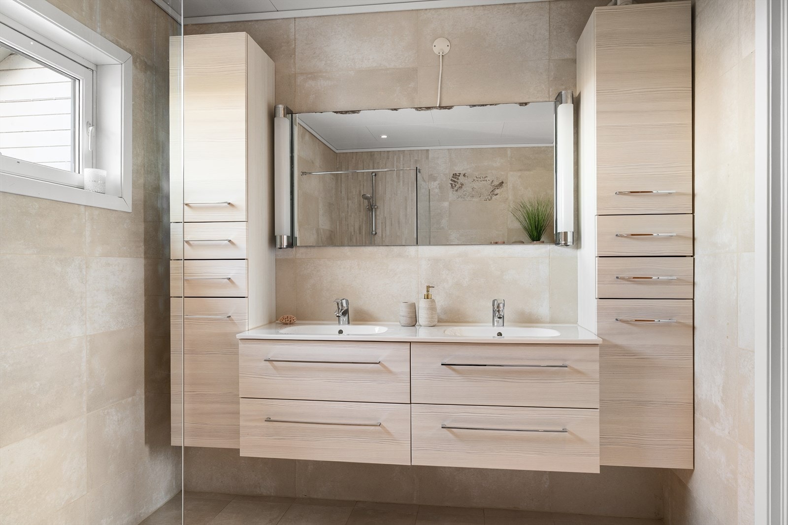 Hovedbadet er helfliset og innredet med doble servanter, vegghengt toalett og dusjhjørne. Galleribilde