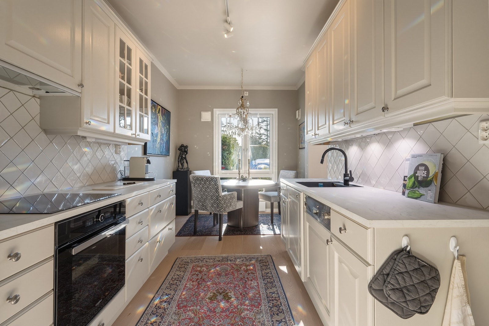 Lyst og delikat kjøkken med spiseplass med utsyn mot hage. Galleribilde